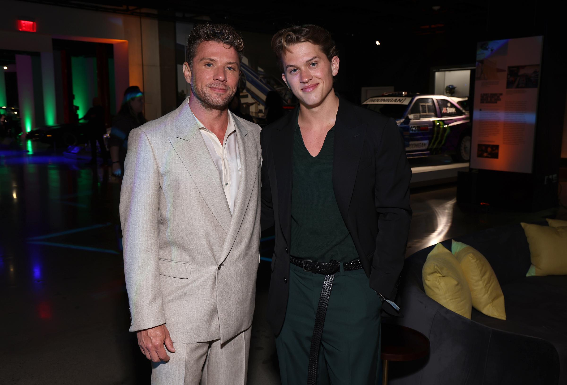 Deacon and Ryan Phillippe are seen posing once again inside the "Motorheads" screening venue, the warm father-son moment captured amid a gallery of classic cars and softly lit interiors at the Petersen Automotive Museum.