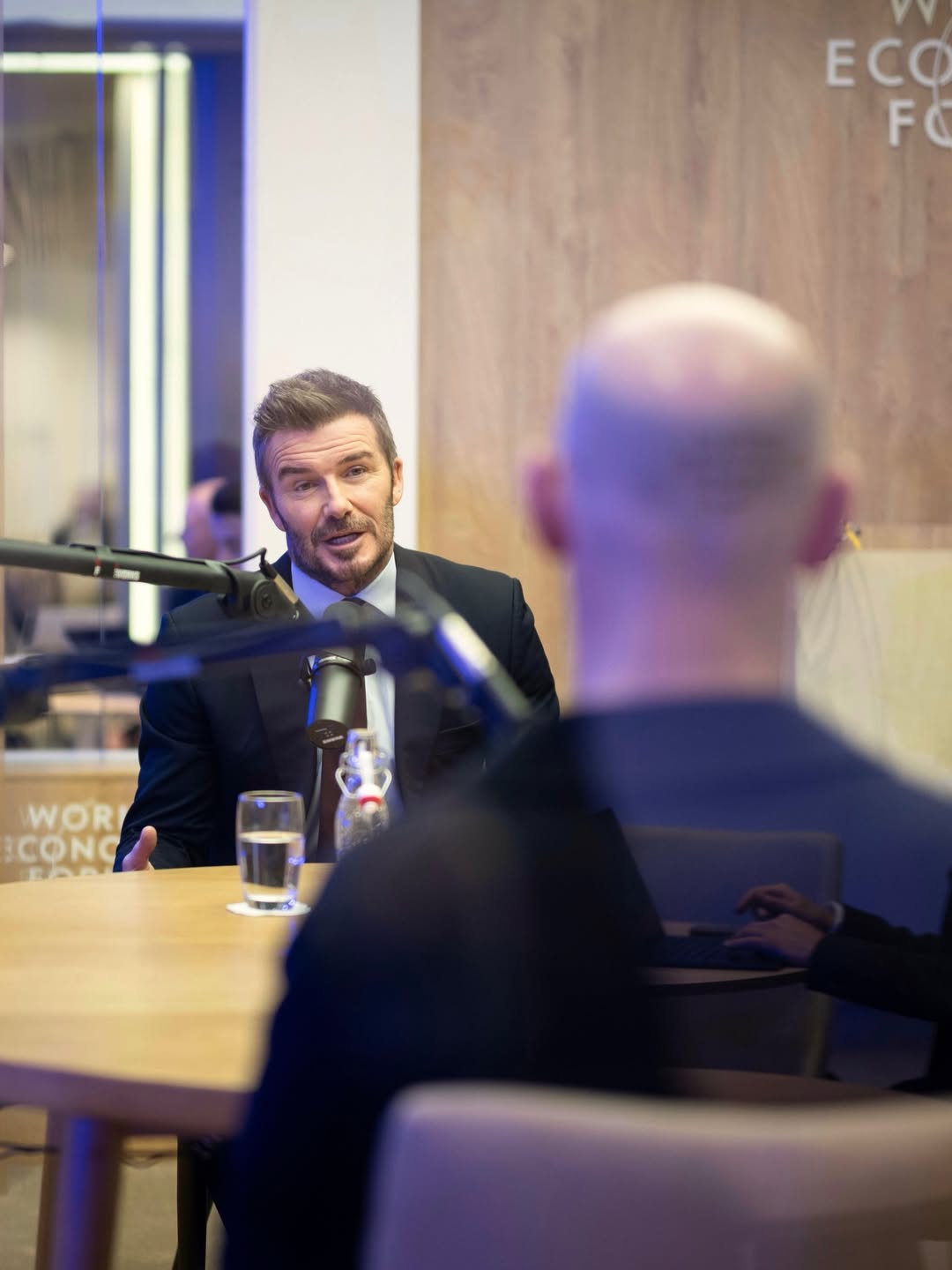 David Beckham speaks into the mic during a podcast recording at the World Economic Forum in Davos on 20 January 2026, keeping his composure as global attention swirled around the Beckham family drama unfolding behind the scenes. | Source: Instagram/hellomag