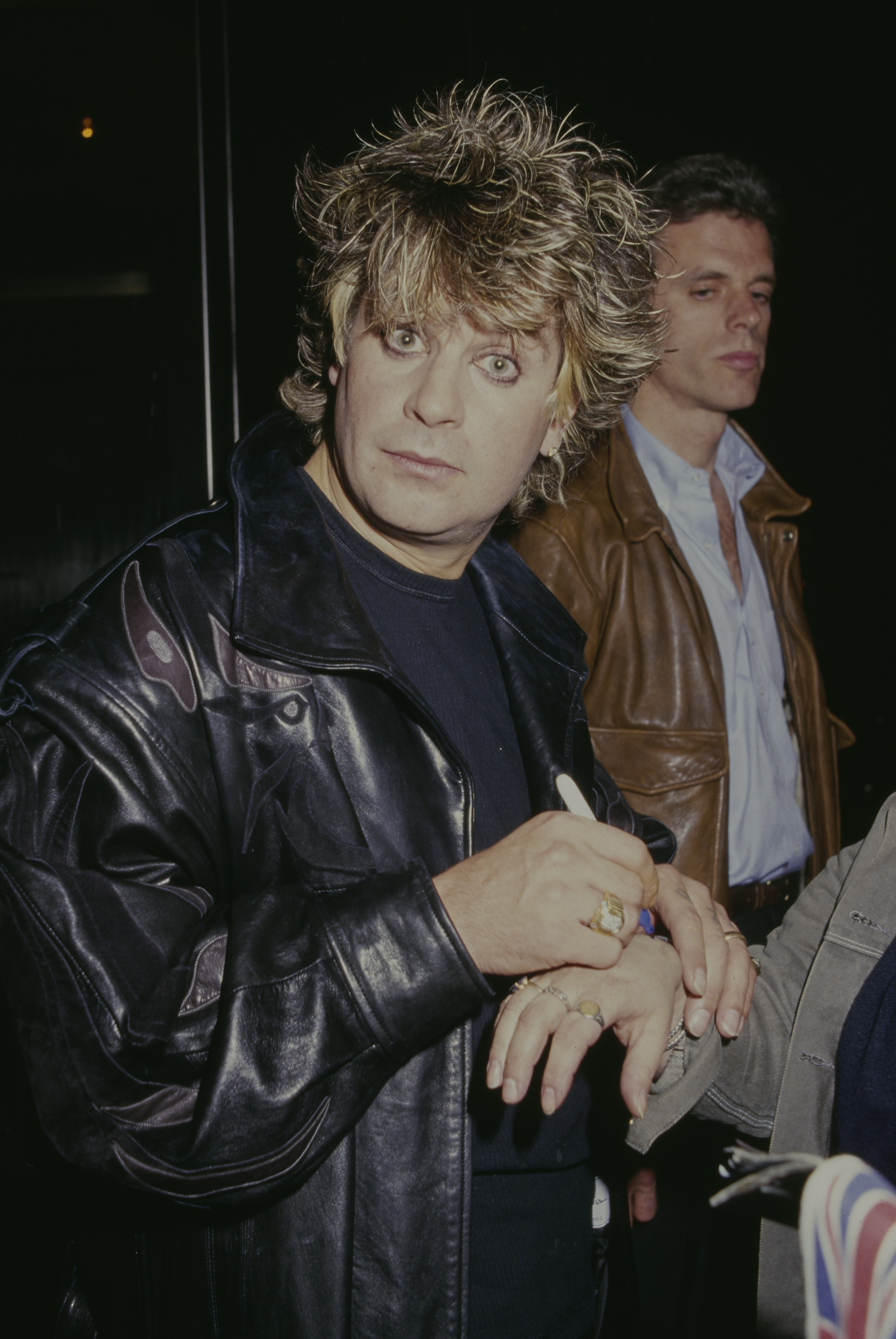 Ozzy Osbourne signing the back of a person's hand as he attended an event in 1985. | Source: Getty Images