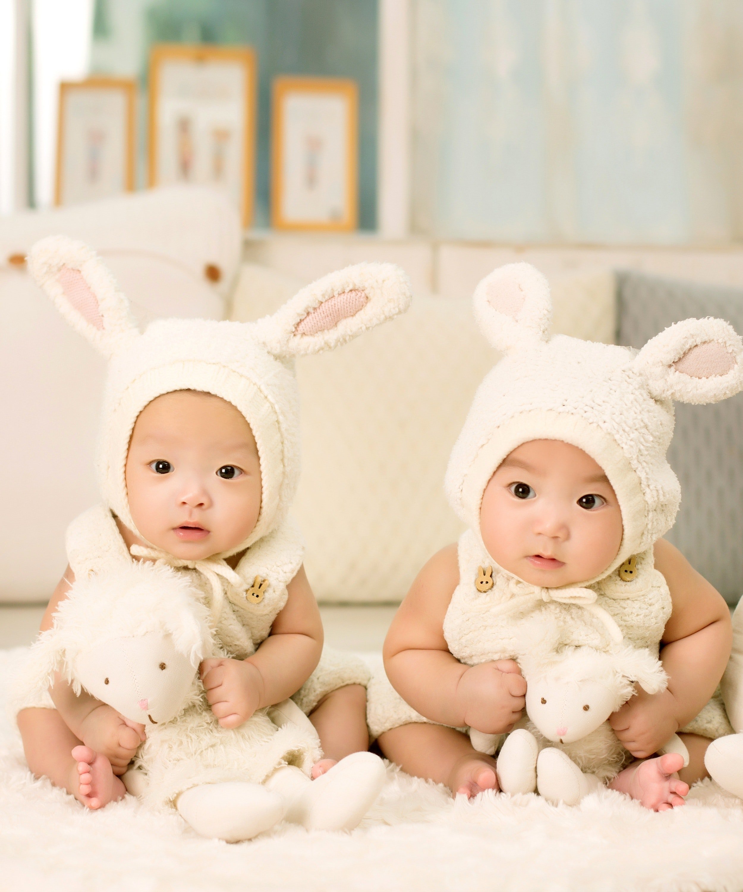 Dos bebés con trajes de conejos sentados en una cama. | Foto: Pexels