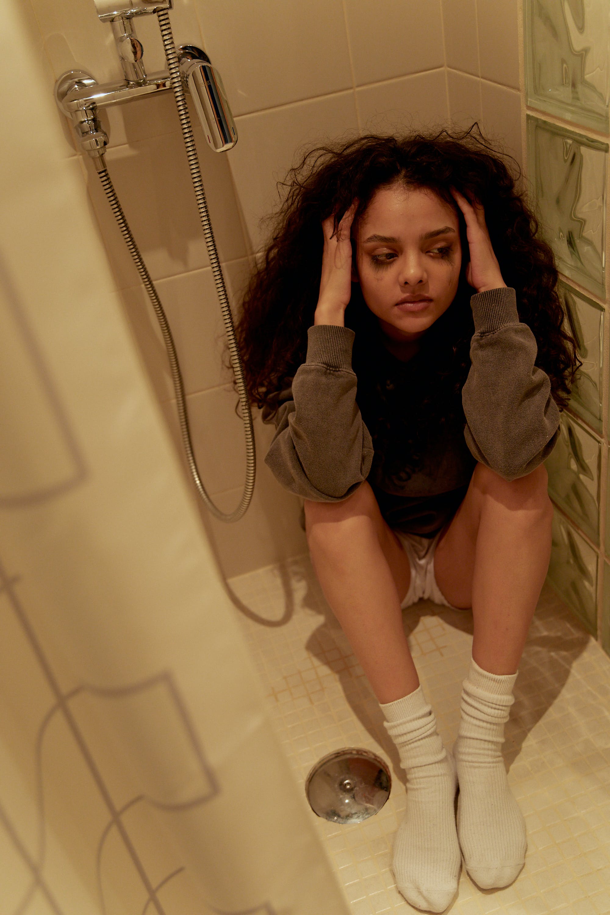 An upset young woman crying while sitting on a shower floor | Source: Pexels