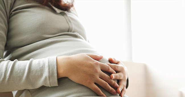 A pregnant woman holding her growing belly. | Source: Shutterstock