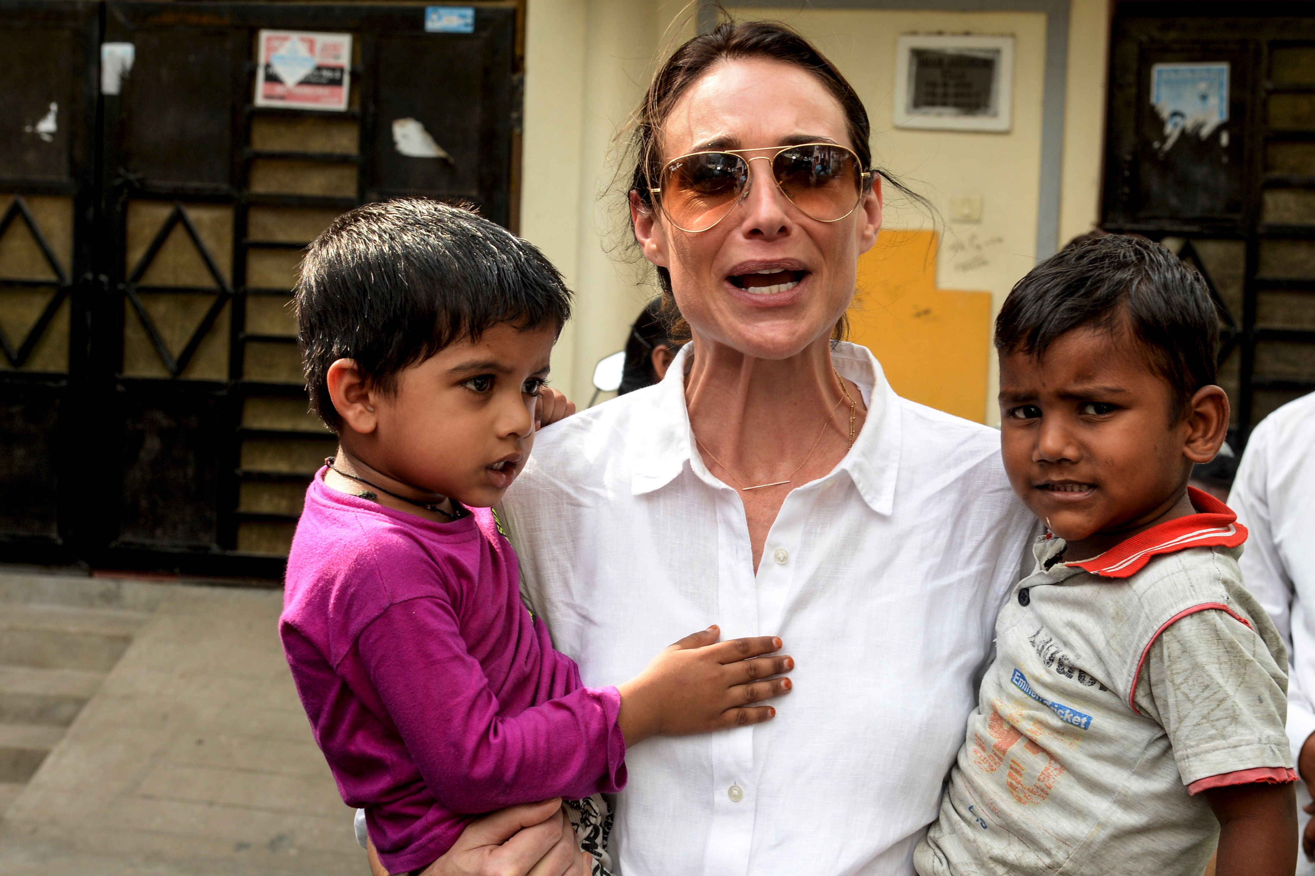 Claire Forlani holding children during a field visit to meet Tuberculosis (TB) survivors in the Malakpet slum area of Hyderabad, India, on October 29, 2019. | Source: Getty Images