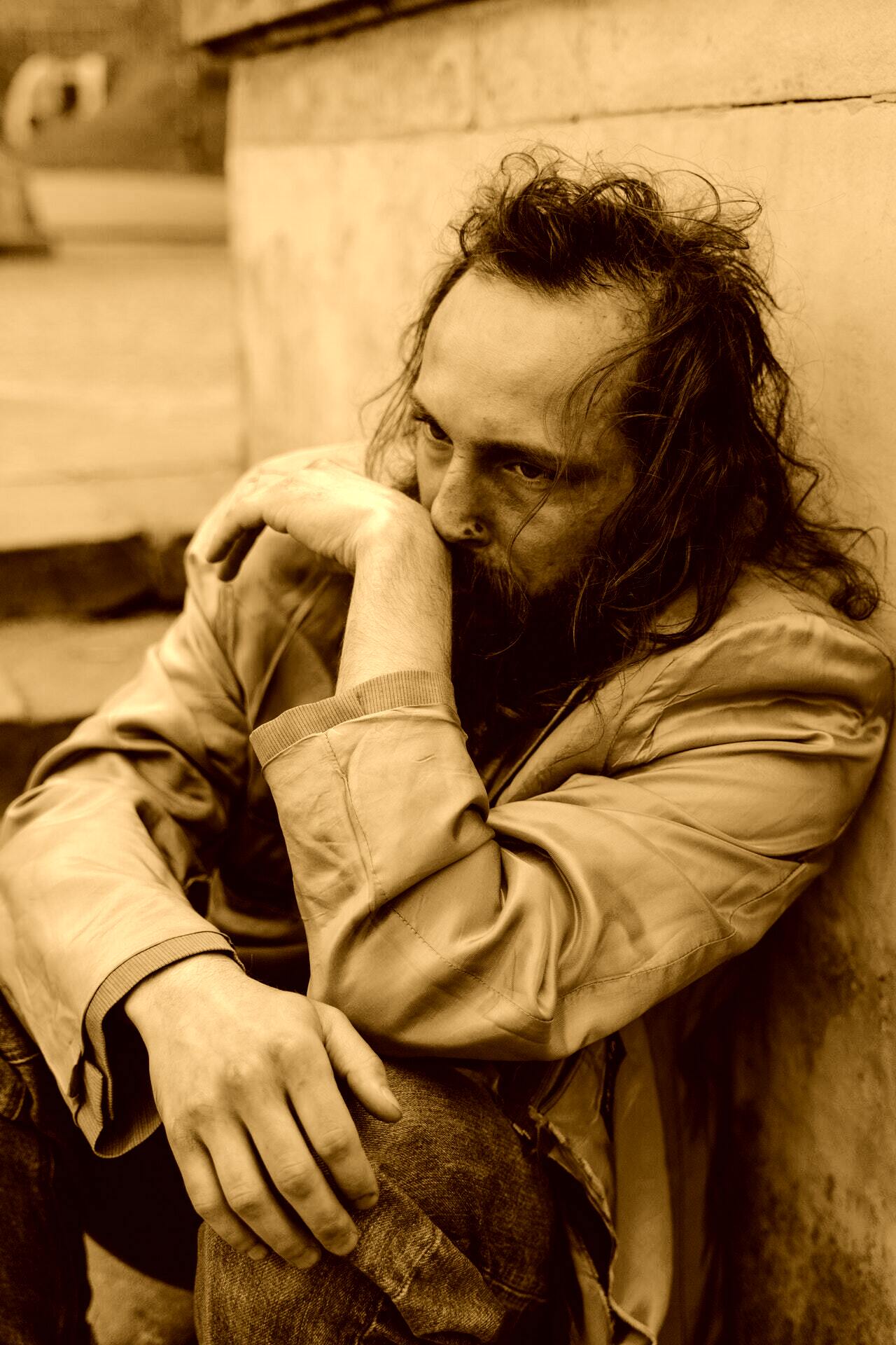 Indigente sentado en el piso con una expresión triste. | Foto: Pexels
