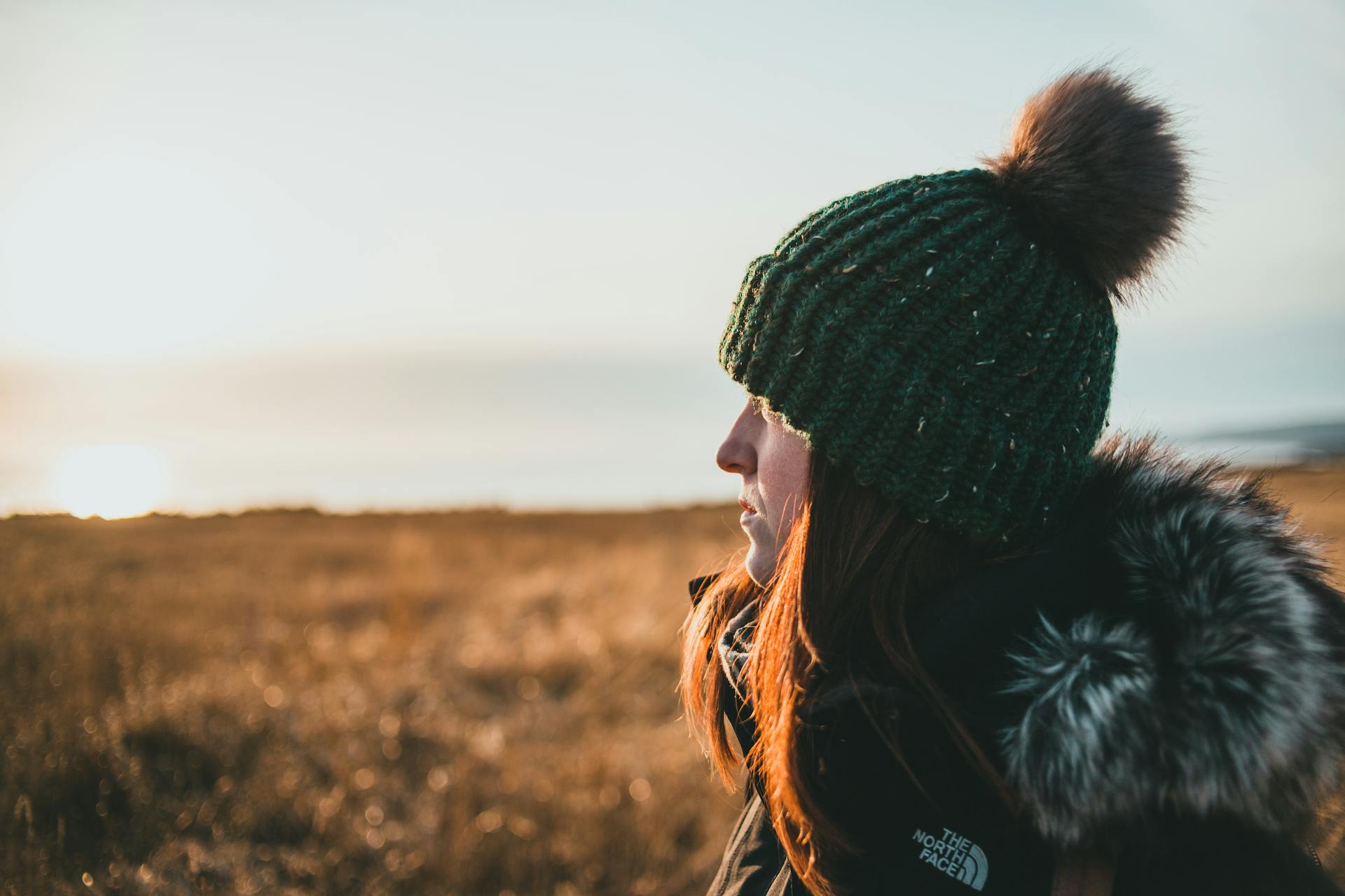 A closeup shot of a woman admiring nature on a grassy seashore at sundown | Source: Pexels