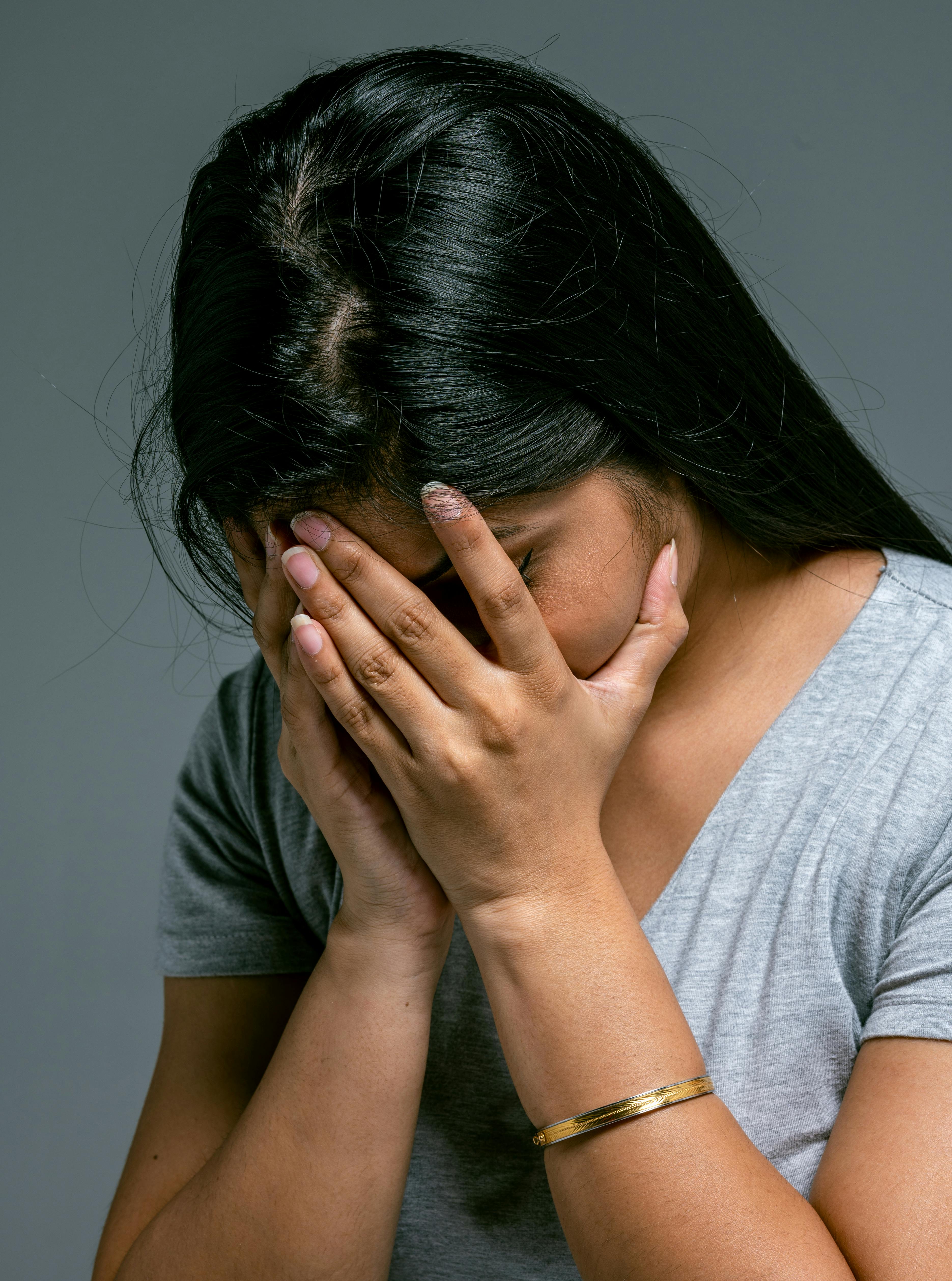 A woman covering her face with her head down | Source: Pexels