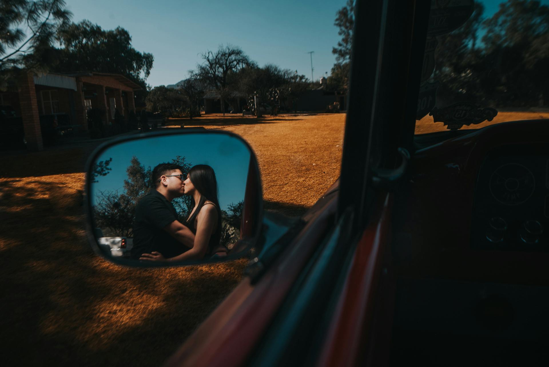 A reflection of a couple kissing in a car's side mirror | Source: Pexels