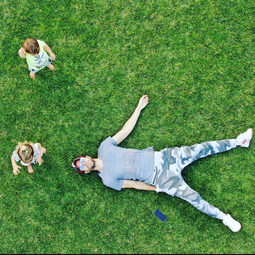Enrique Iglesias lying on the grass while Nicholas and Lucy Iglesias surround him, from a post dated January 18, 2020 | Source: Instagram/enriqueiglesias