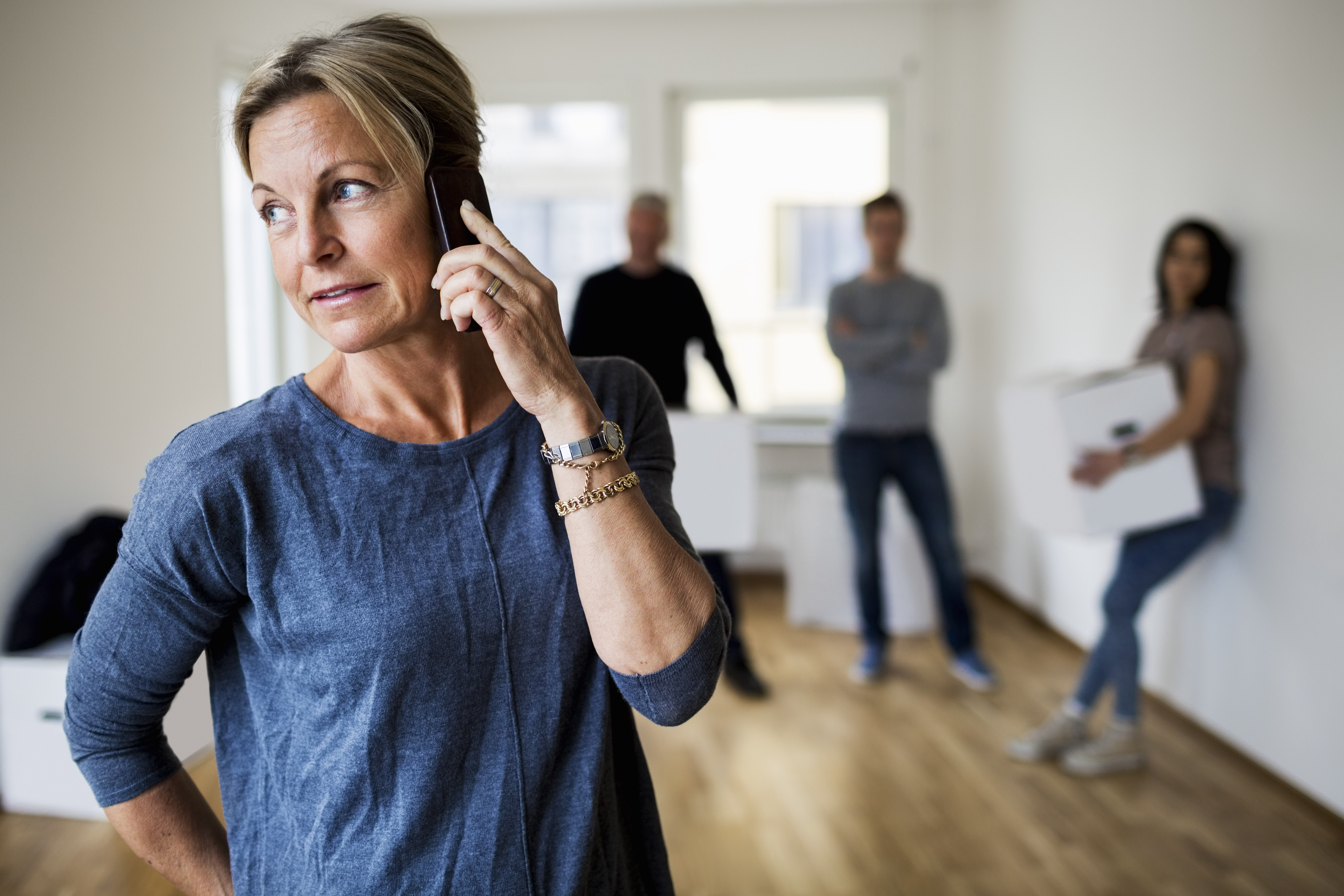 Mature woman on the phone with her family behind her | Source: Getty Images