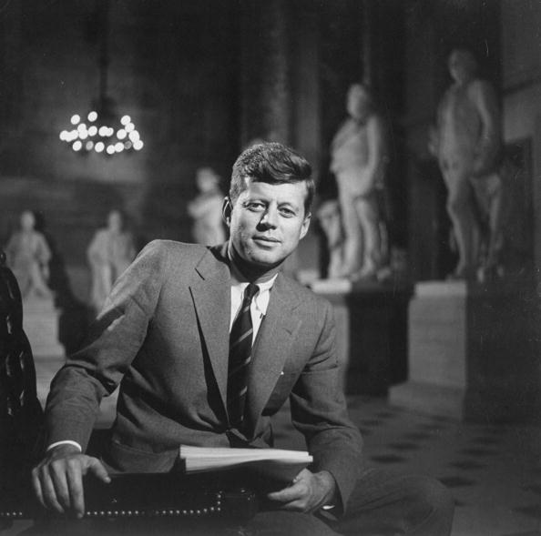 Photo of Senator John F. Kennedy seated in a museum with statues | Photo: Getty Images