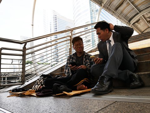  Photo of a business man and homeless man sitting by the street | Photo: Getty Images