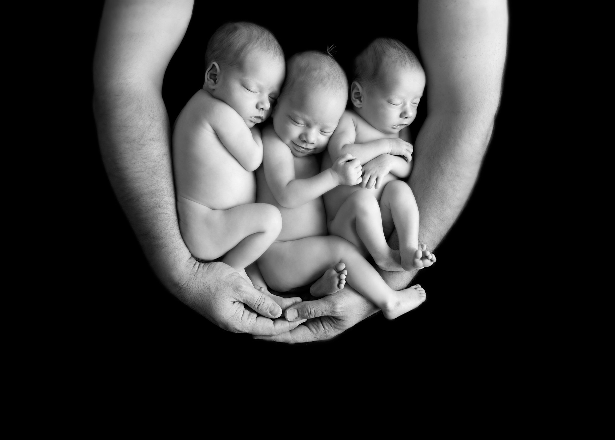 The image of a hand holding three new born babies | Photo: Getty Images