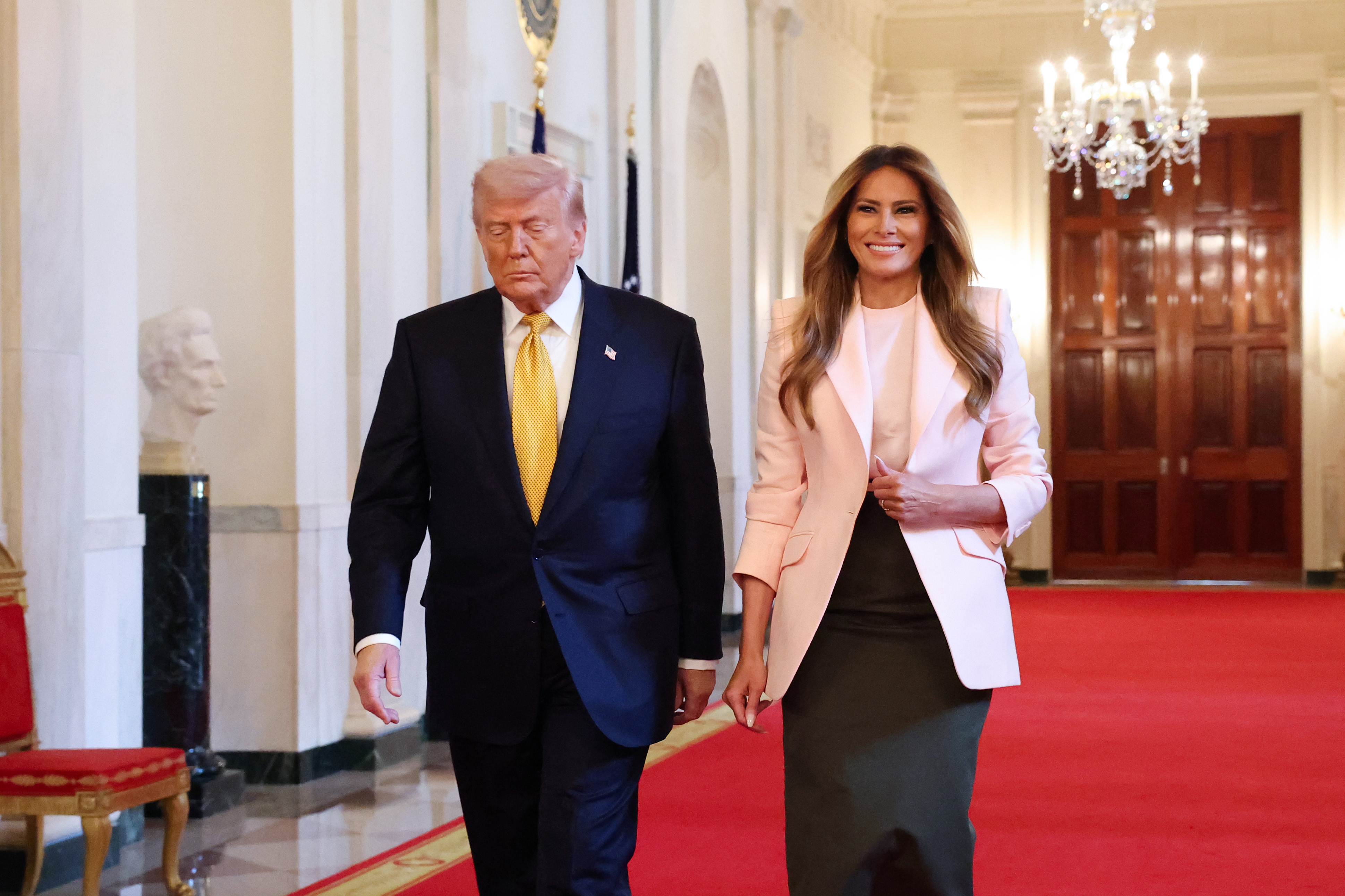 Donald Trump and Melania Trump walk down the Cross Hall as they arrive for a military mothers celebration in the East Room of the White House on May 6, 2026, in Washington, DC | Source: Getty Images