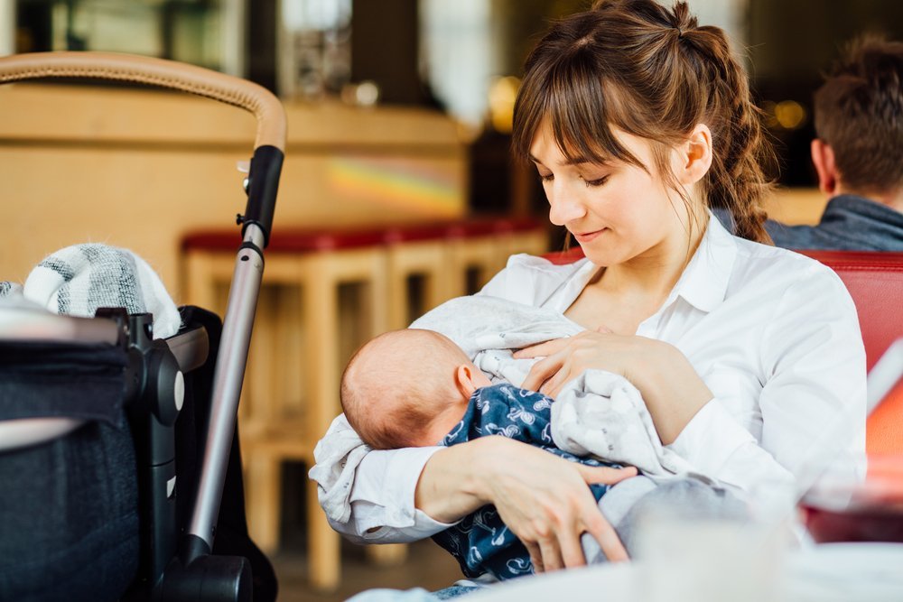 Una joven madre amamantando a su bebé en un café mientras está tomando un té. Fuente: Shutterstock