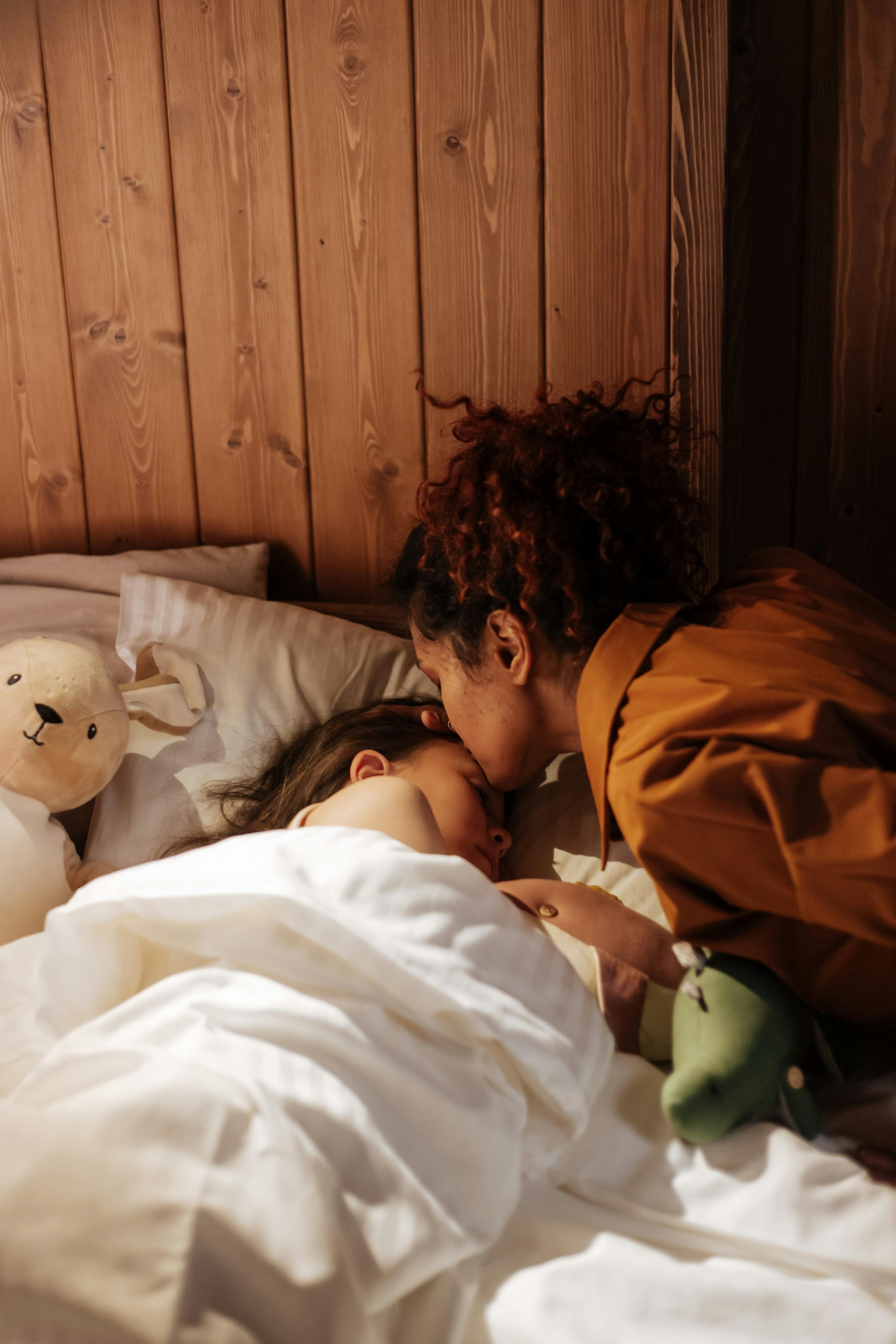 A mother tucking her daughter in bed | Source: Pexels