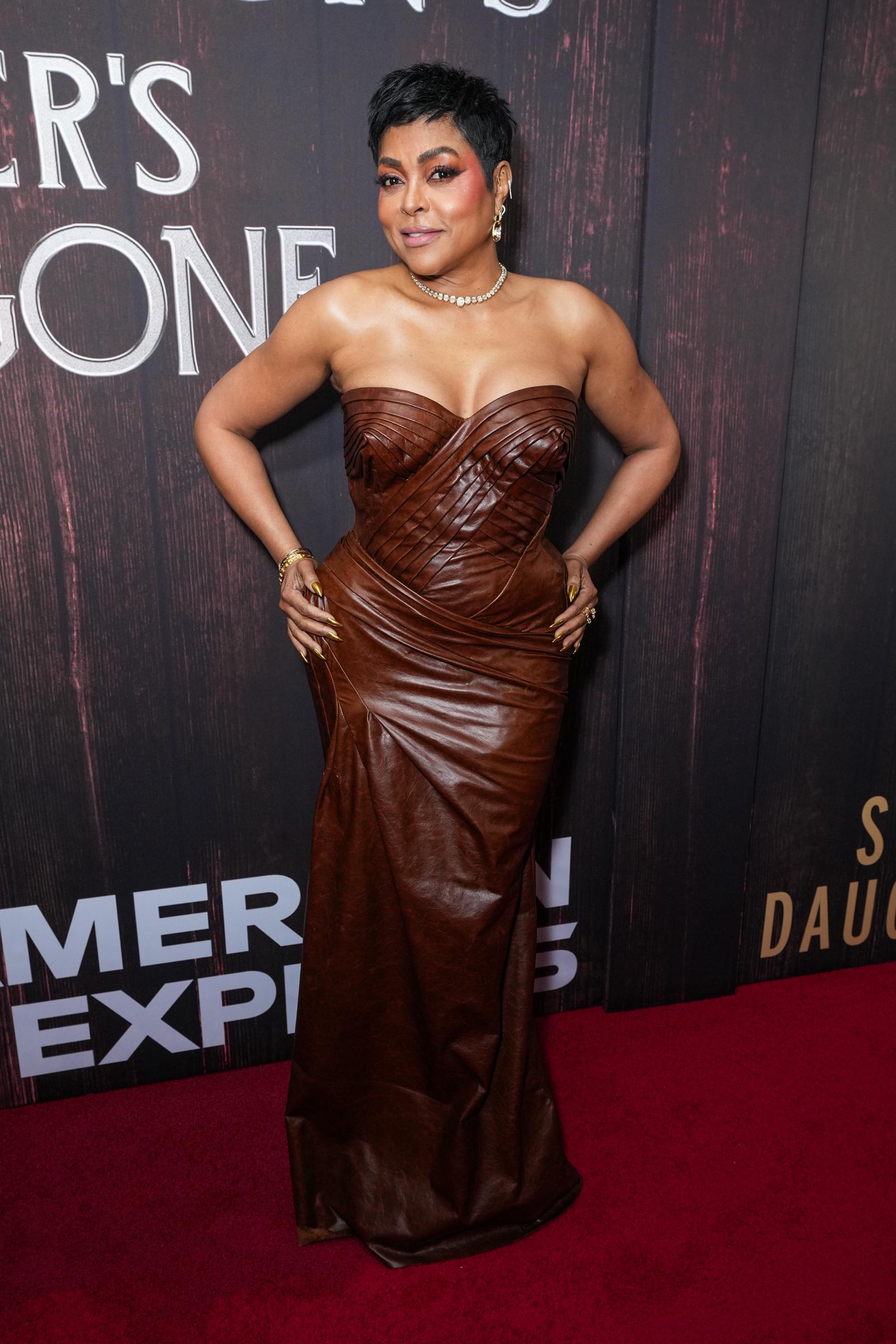 Taraji P. Henson attends "Joe Turner’s Come and Gone" opening night in a strapless brown leather gown with layered, sculpted panels, standing with both hands anchored at her hips as she faces the backdrop.