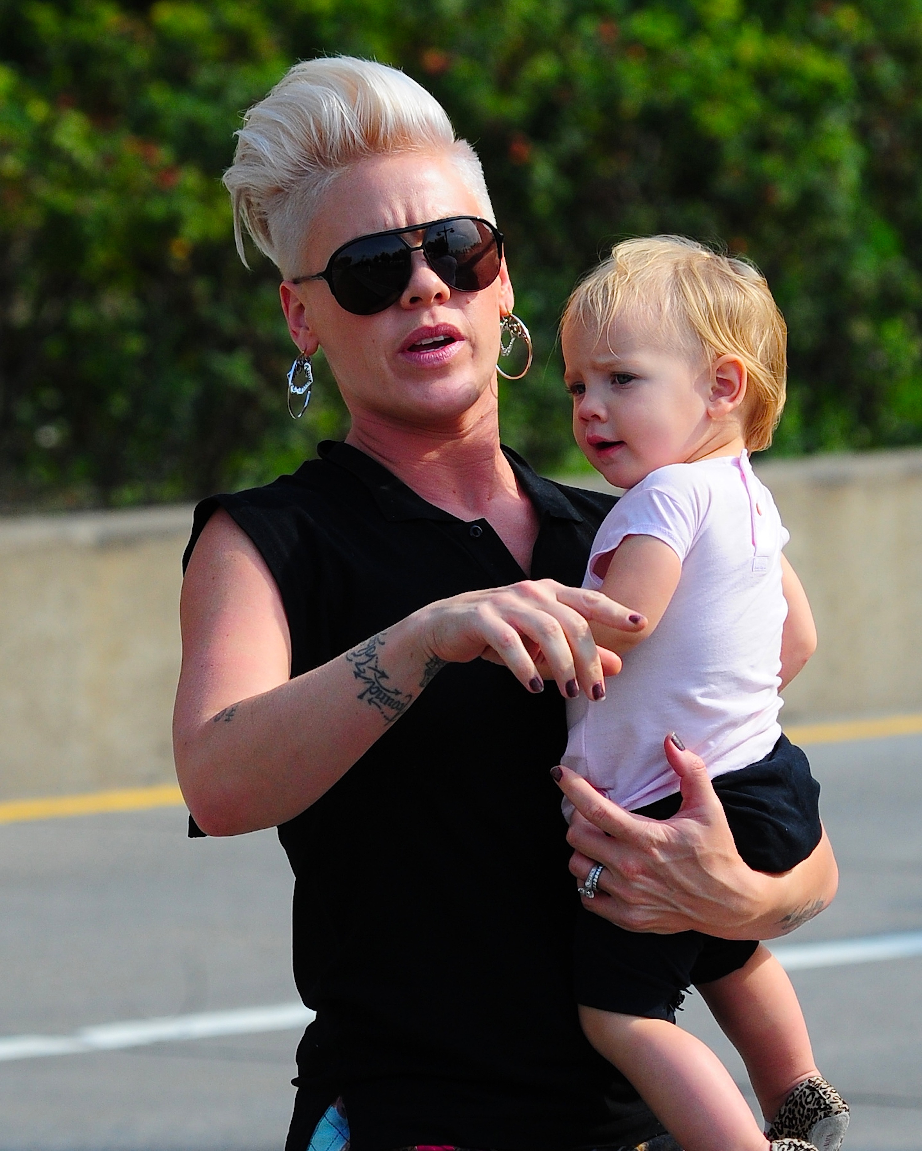 Pink holds Willow Sage Hart in Tribeca on September 17, wearing dark sunglasses and a sleeveless black top. Willow looks around in a white shirt and black shorts during the New York City outing.