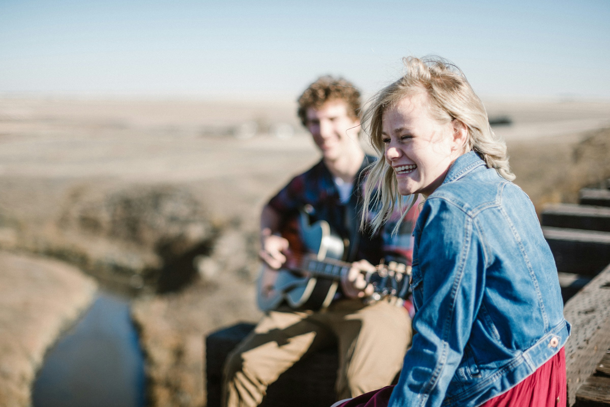 A woman smiling while sitting next to a man playing a guitar | Source: Unsplash