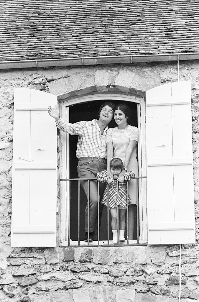 Portrait de Pierre PERRET chez lui à la fenêtre avec son épouse et sa fille Julie. | Photo : Getty Images