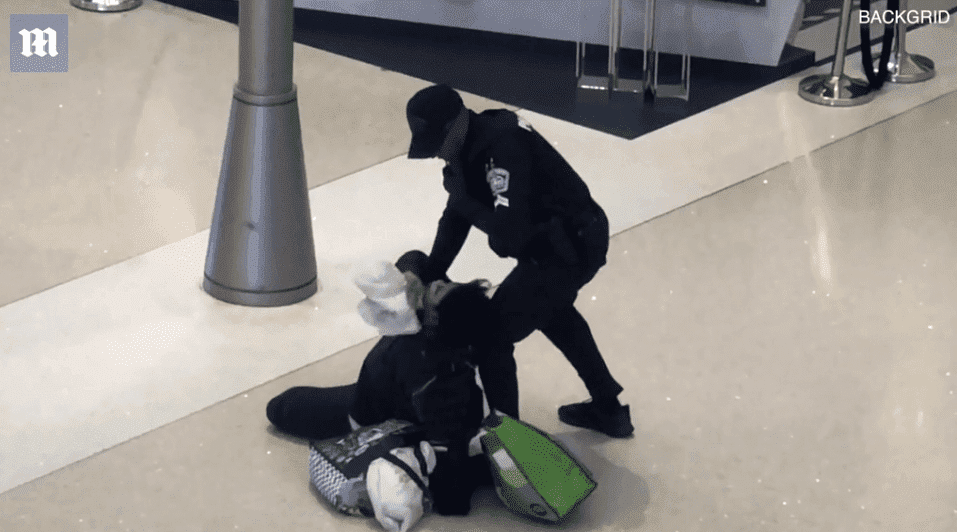 A woman is pined to the ground by a police officer at LAX | Photo: Daily Mail/BackGrid