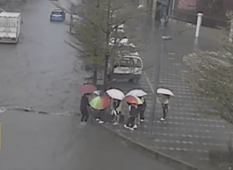 Maestra cargando a sus alumnos sobre una calle inundada en China. | Imagen: YouTube/Daily Mail Maestra cargando a sus alumnos sobre una calle inundada en China. | Imagen: YouTube/Daily Mail