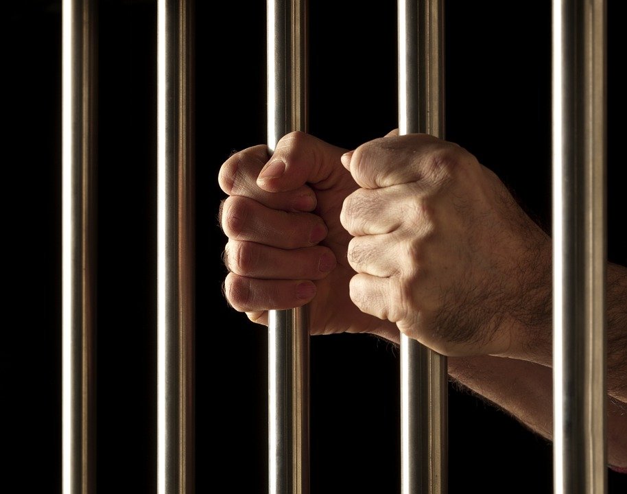 Hombre encarcelado sosteniendo las rejas. | Imagen: Pixabay