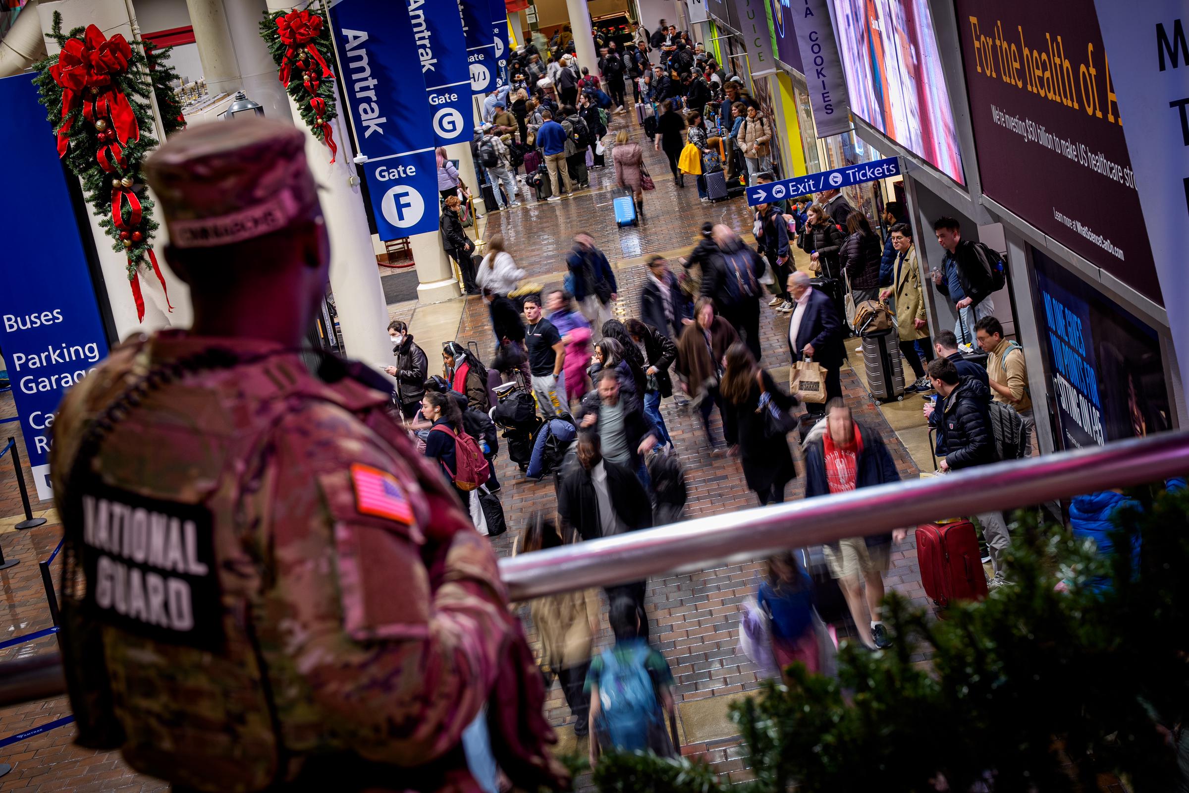 A member of the National Guard stands above Amtrak gates as travelers move through Union Station on November 25, 2025, in Washington, DC | Source: Getty Images