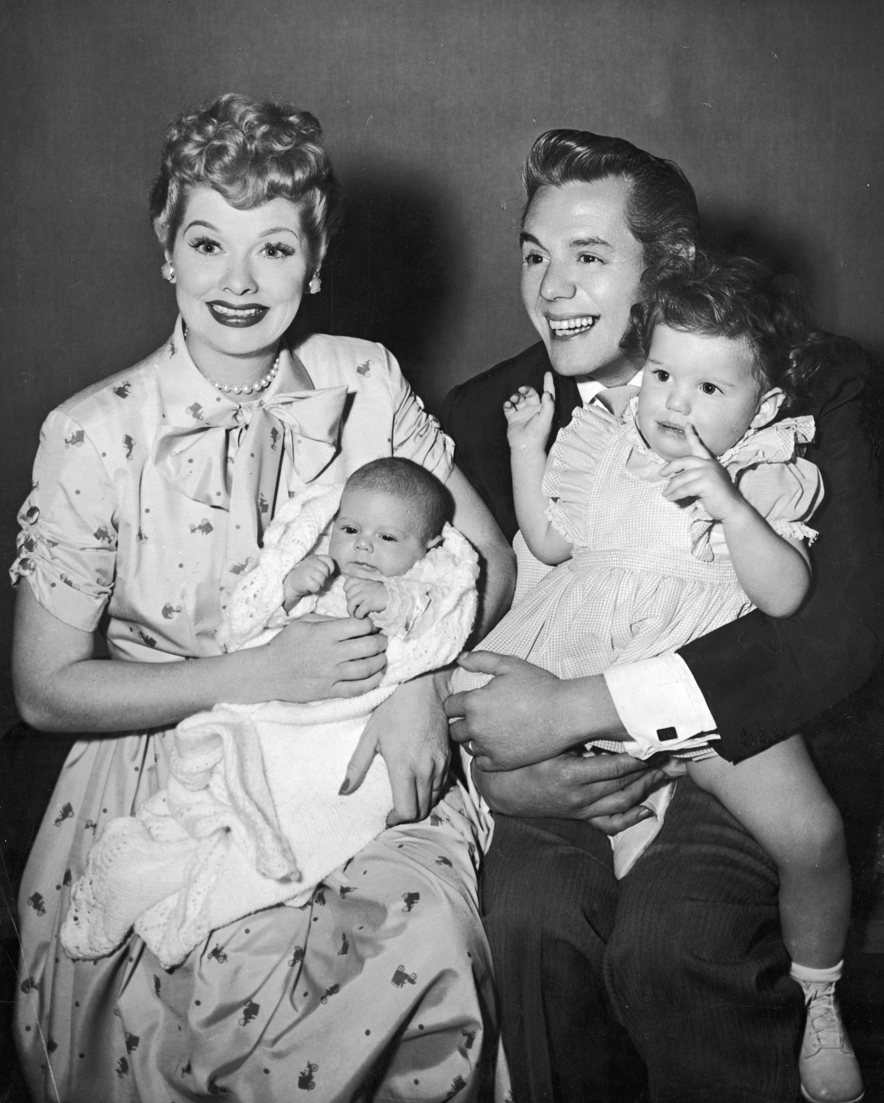 American actors and comedian Lucille Ball and her husband, Cuban-born actor and bandleader Desi Arnaz, laugh and smile while holding their two children, Desi Jr and Lucie | Source: Getty  Images