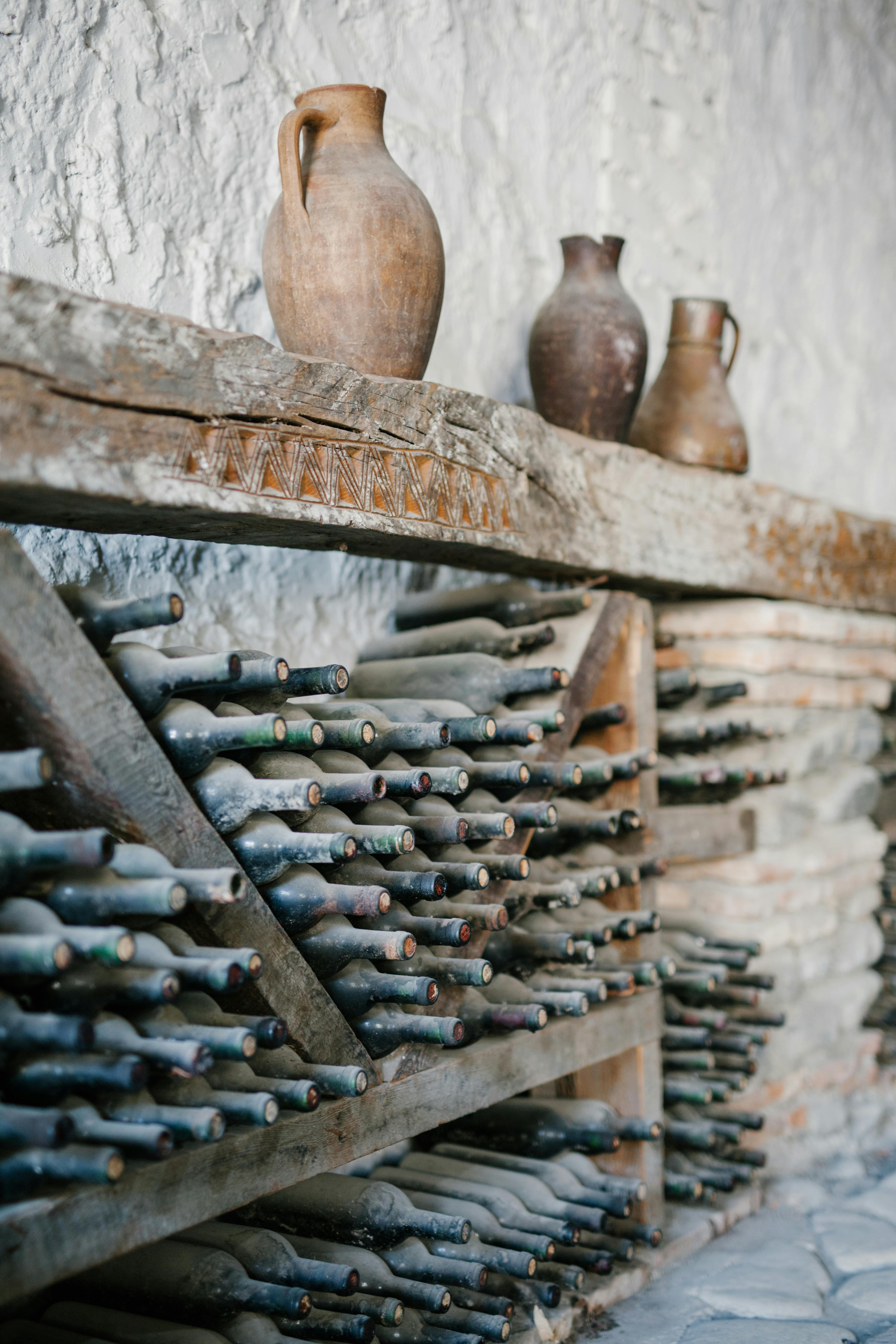 Wooden shelves with dusty glass bottles of wine | Source: Pexels