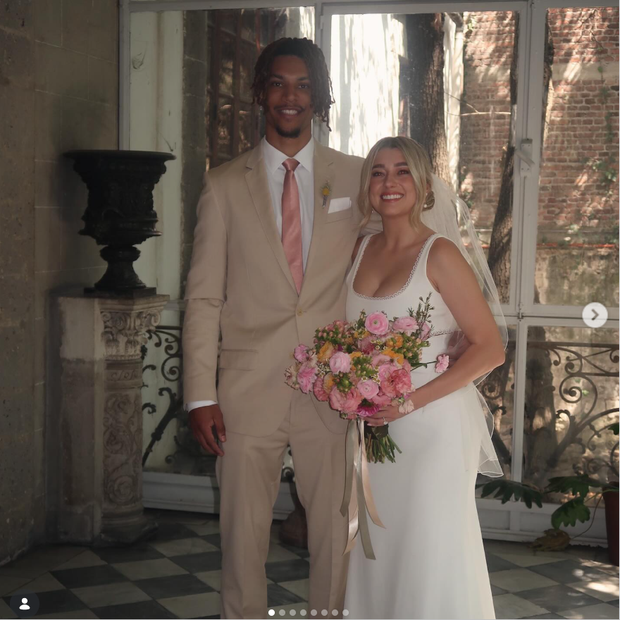 Brandon Clarke stands beside his sister on her wedding day as she smiles while holding a bouquet of pink flowers in a white gown and veil. | Source: Instagram/brandon_clarke23