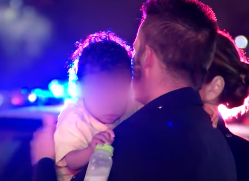 Police officer comforts a baby after his mom fled the accident scene and left him behind | Photo: Youtube/Inside Edition