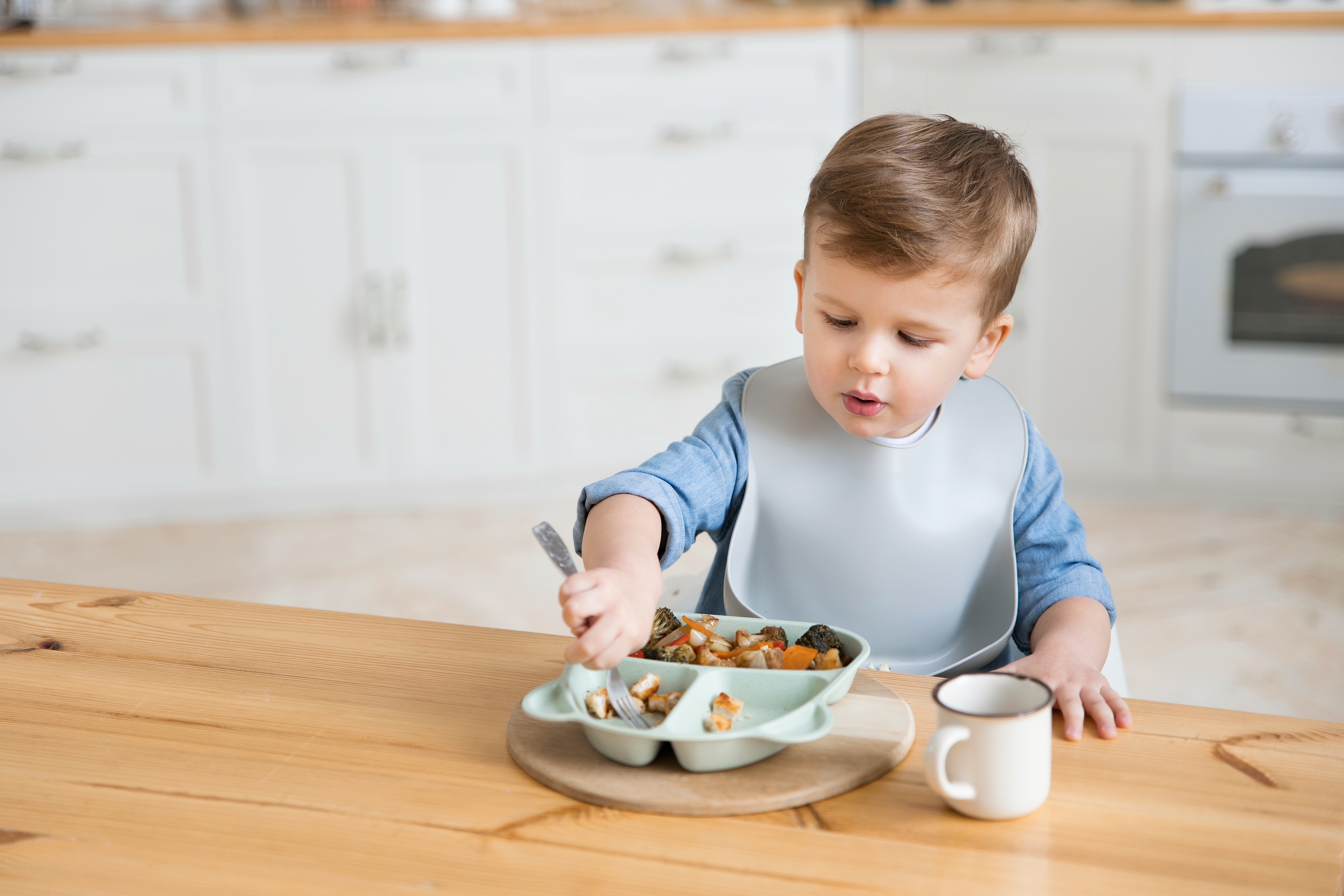 Toddler eating while wearing a bib | Source: Shutterstock