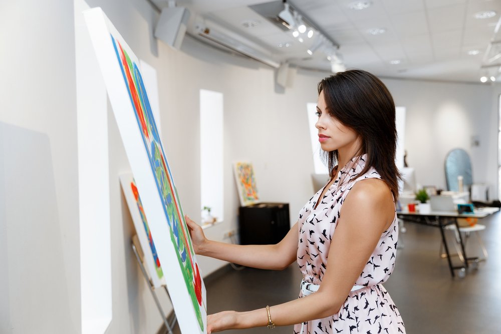Una joven revisando una obra de arte en una galería. | Foto: Shutterstock