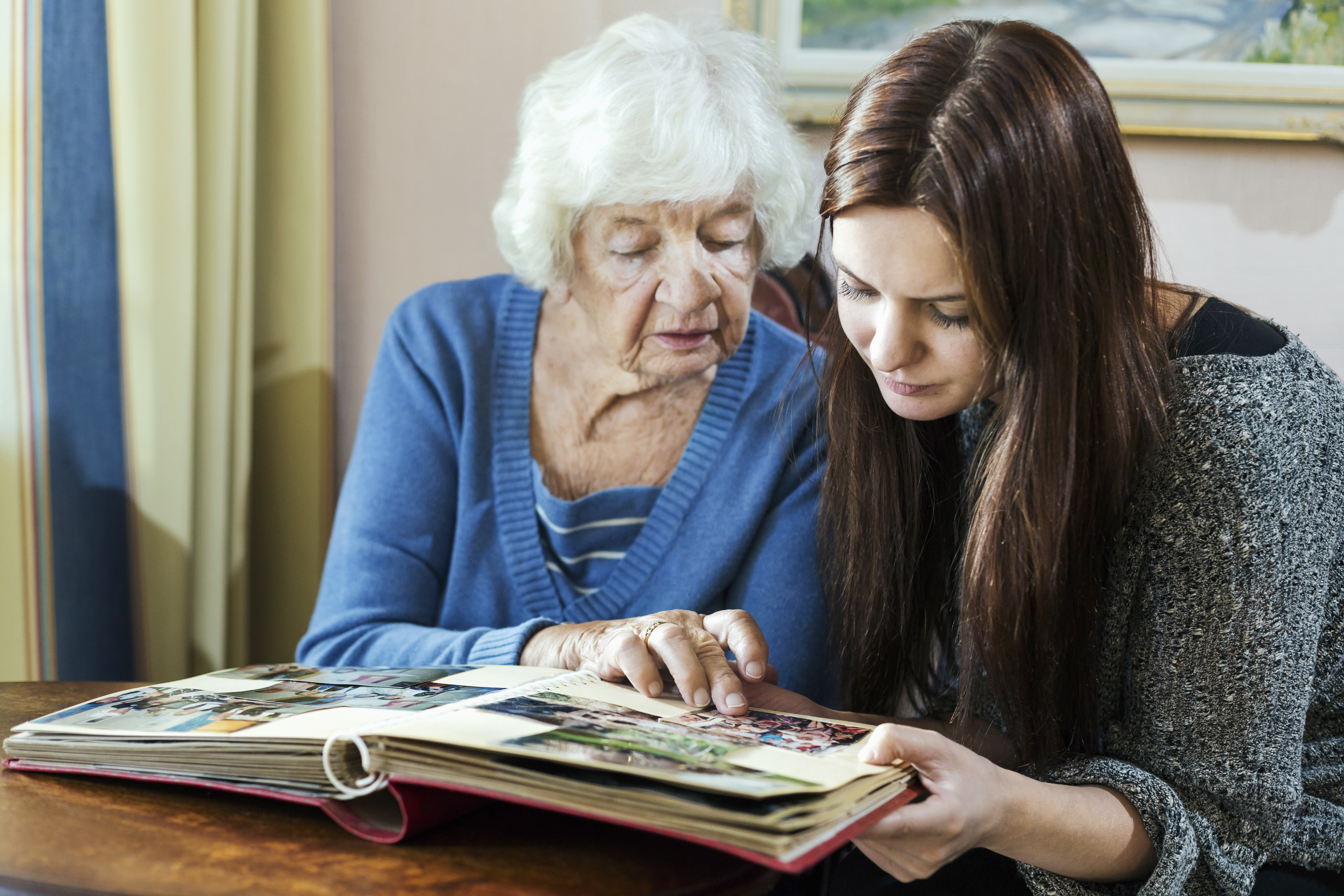 Grandmother and granddaughter looking at photo album in house | Source: Getty Images