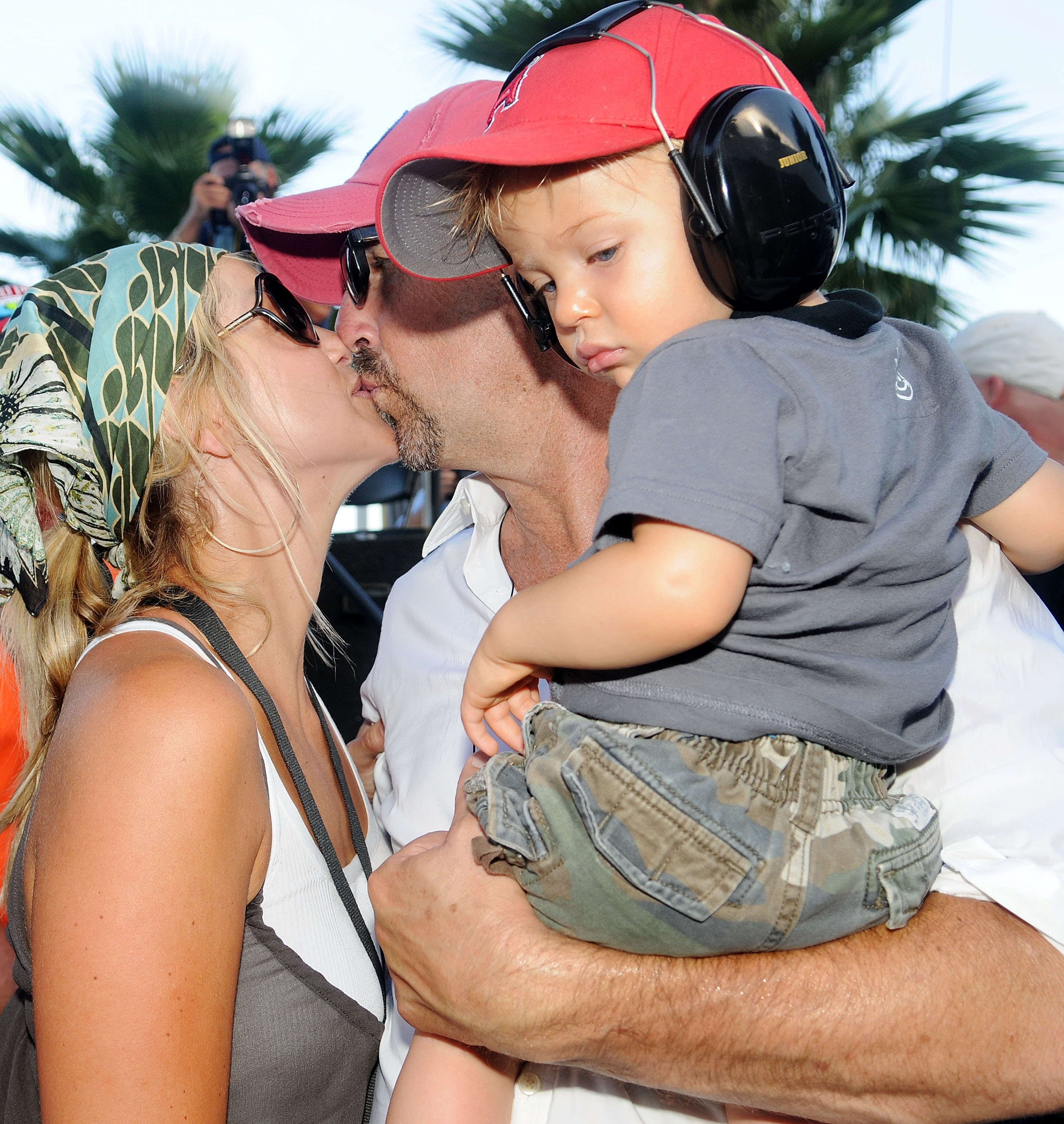 Kevin Costner kisses his wife Christine Baumgartner in the company of their son Cayden Costner during the Sprint Fan Zone before the NASCAR Sprint Cup Series Coke Zero 400 at Daytona International Speedway on July 5, 2008 in Daytona Beach, Florida. | Source: Getty Images
