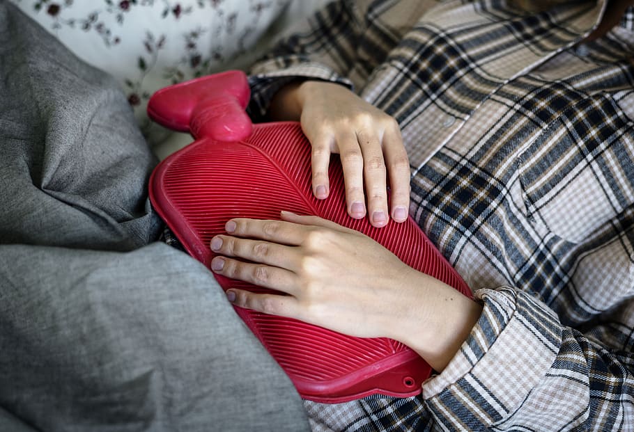 Persona con una bolsa térmica sobre el vientre mientras está recostada. | Foto: Piqsels