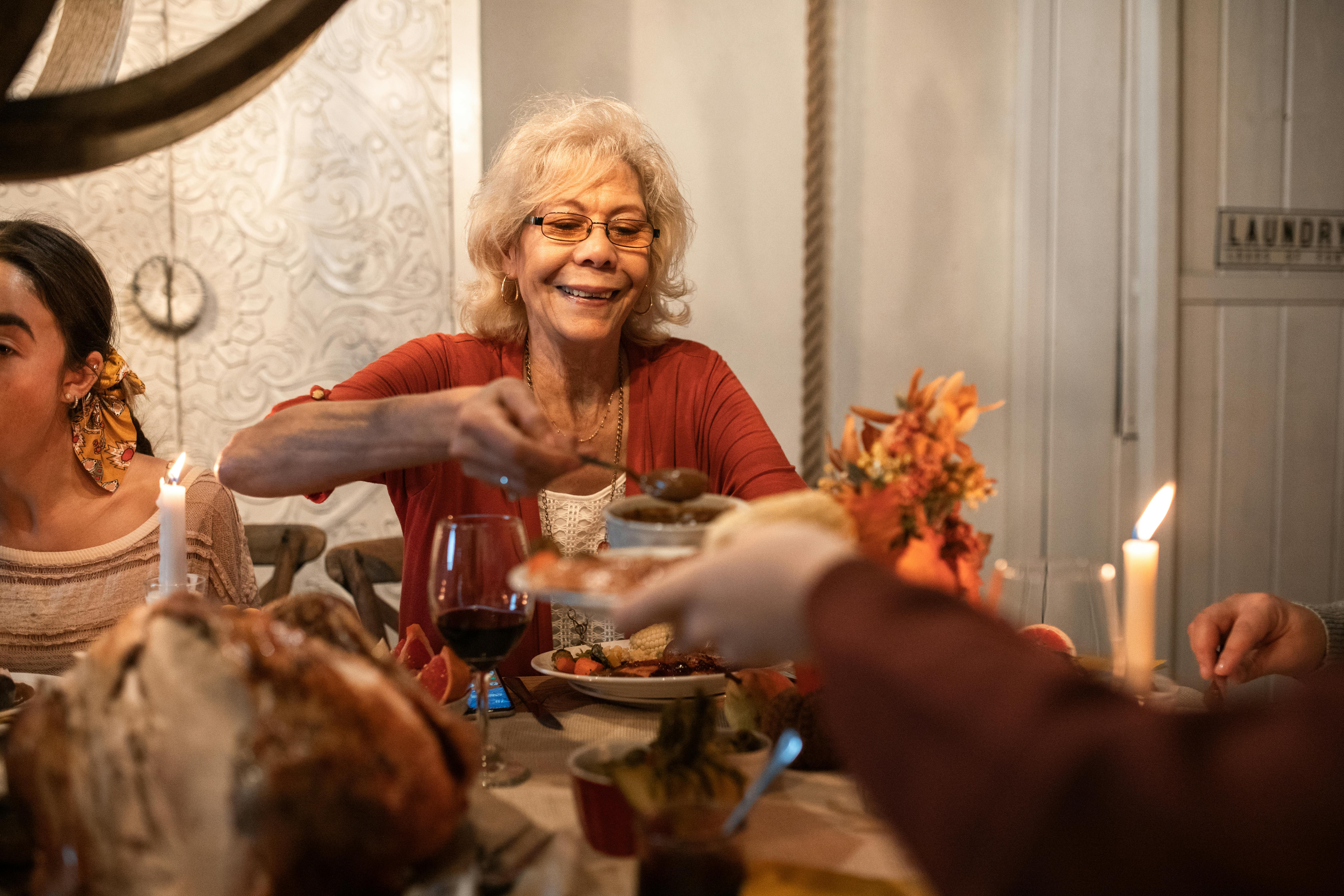 An elderly woman serving dinner at a table | Source: Pexels