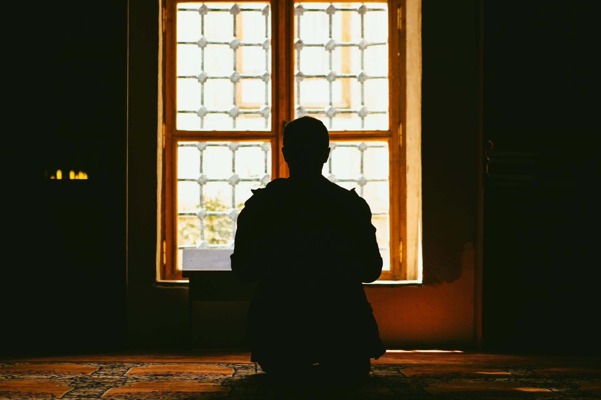 A silhouette of a man sitting in front of a window | Source: Pexels