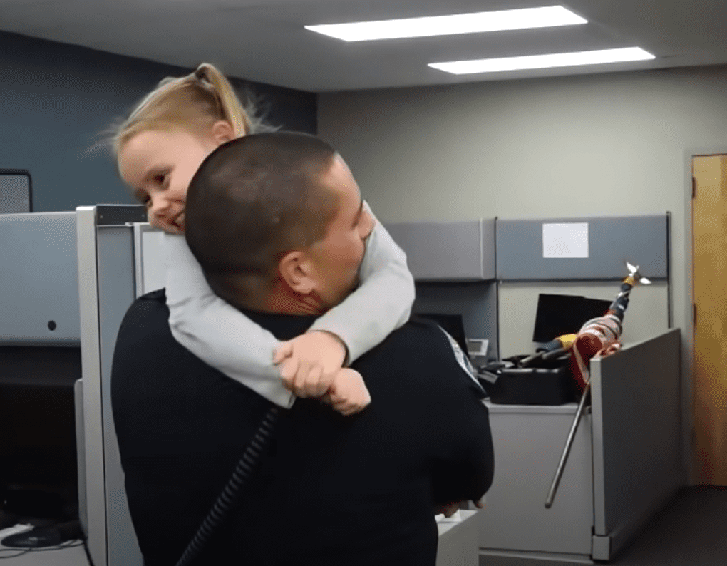 A little girl who came from an abusive home hugs the police officer who adopted her | Photo: Youtube/Inside Edition
