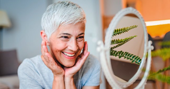 Une femme souriante se regarde dans le miroir. | Photo : Getty Images