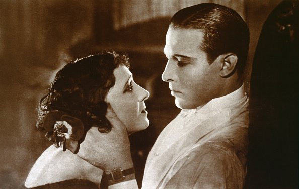 Rudolph Valentino (1895-1926) con Helen d'Algy (1906) en una escena de amor de la película "A Sainted Devil". Fotografía en tonos sepia, imagen promocional Paramount, EE.UU. 1924. | Fuente: Getty Images