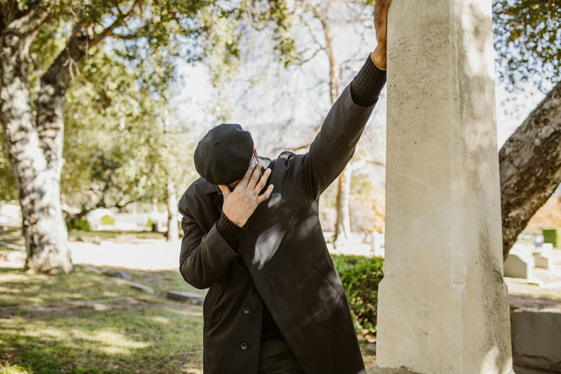 A closeup of a man in a black suit crying in a cemetery | Source: Pexels