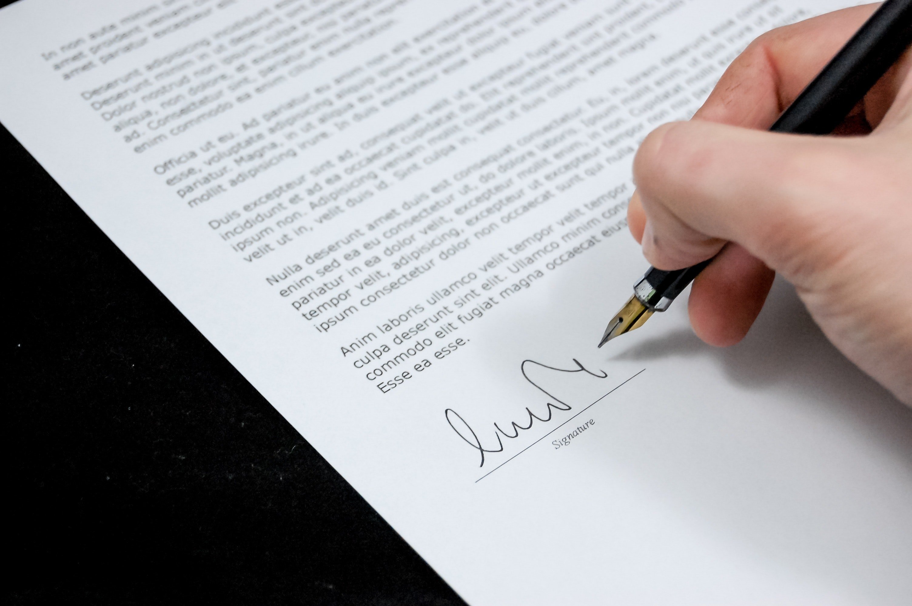 Pictured: A photograph of an individual signing a business document | Source: Pexels  