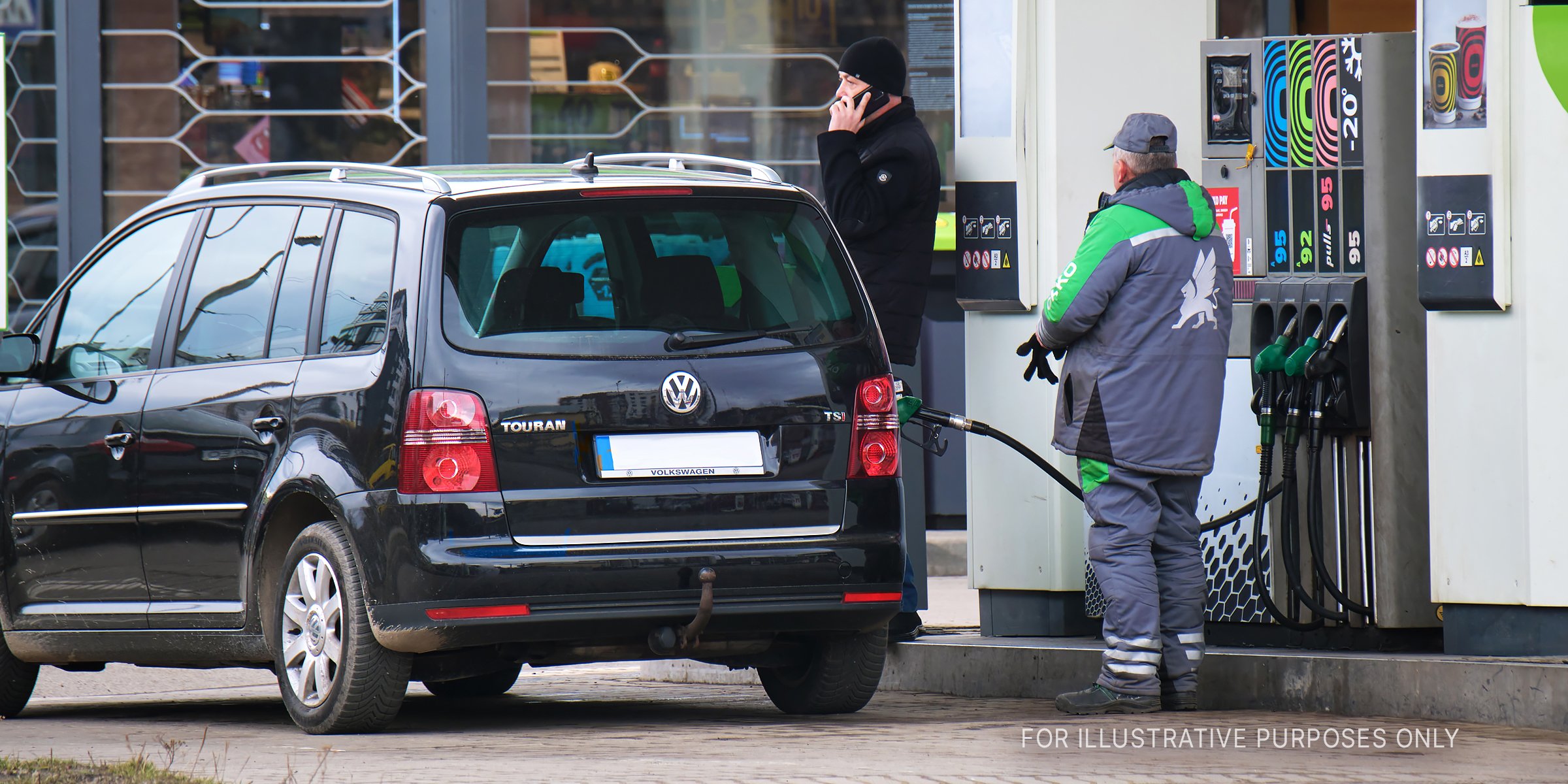 Shutterstock | A gas jockey filling gas in a black car.