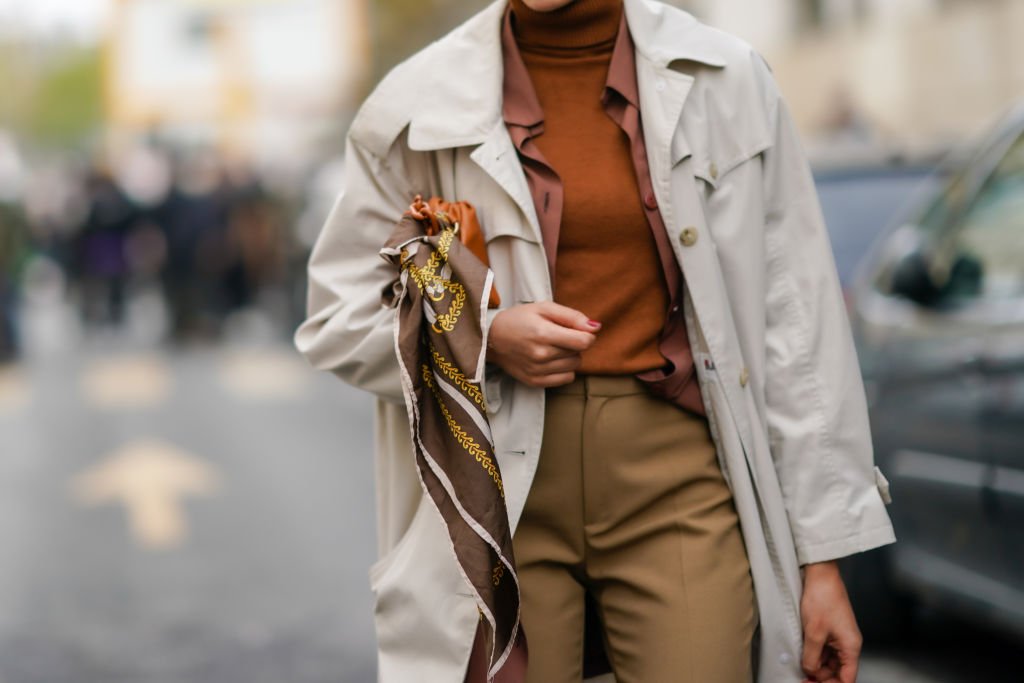 Maria Decremps trägt während der Pariser Modewoche am 30. September 2020 in Paris, Frankreich, goldene Ohrringe, einen Rollkragenpullover aus brauner Wolle, einen beigen Trenchcoat, eine ausgestellte khakifarbene Hose und einen Schal außerhalb von Kenzo. | Quelle: Getty Images
