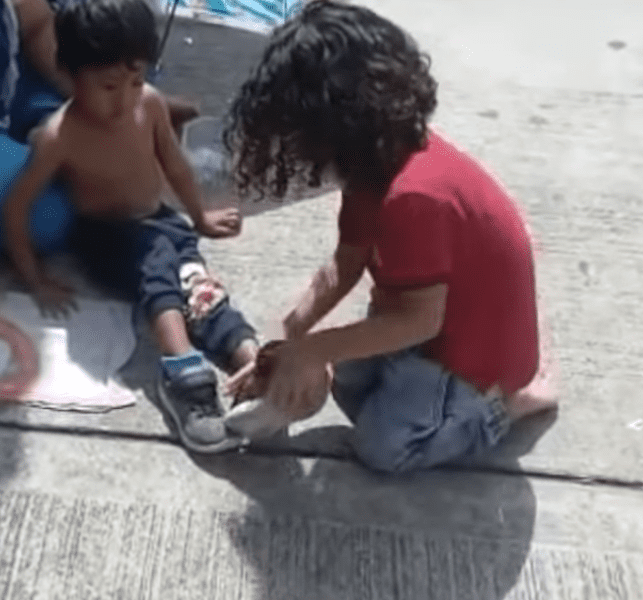 Faizal wearing his socks and shoes for the homeless child. | Source: youtube.com/Sahouli Cheikh Faizal