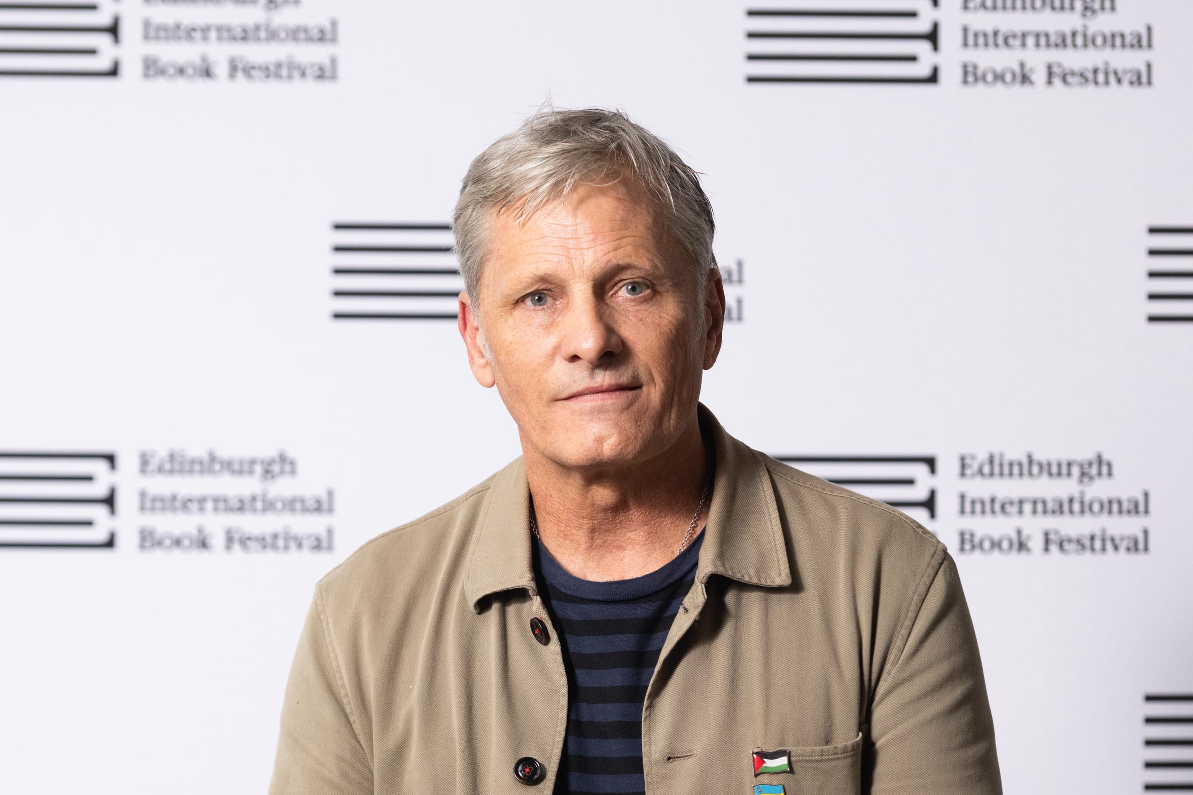On August 24, 2025, Viggo Mortensen appeared at the Edinburgh International Book Festival in Scotland, dressed in a tan jacket and navy striped shirt. With his silver hair and thoughtful gaze, Mortensen cut a composed figure, far removed from battlefields but still carrying the gravitas of a man who once ruled Middle-earth on screen.