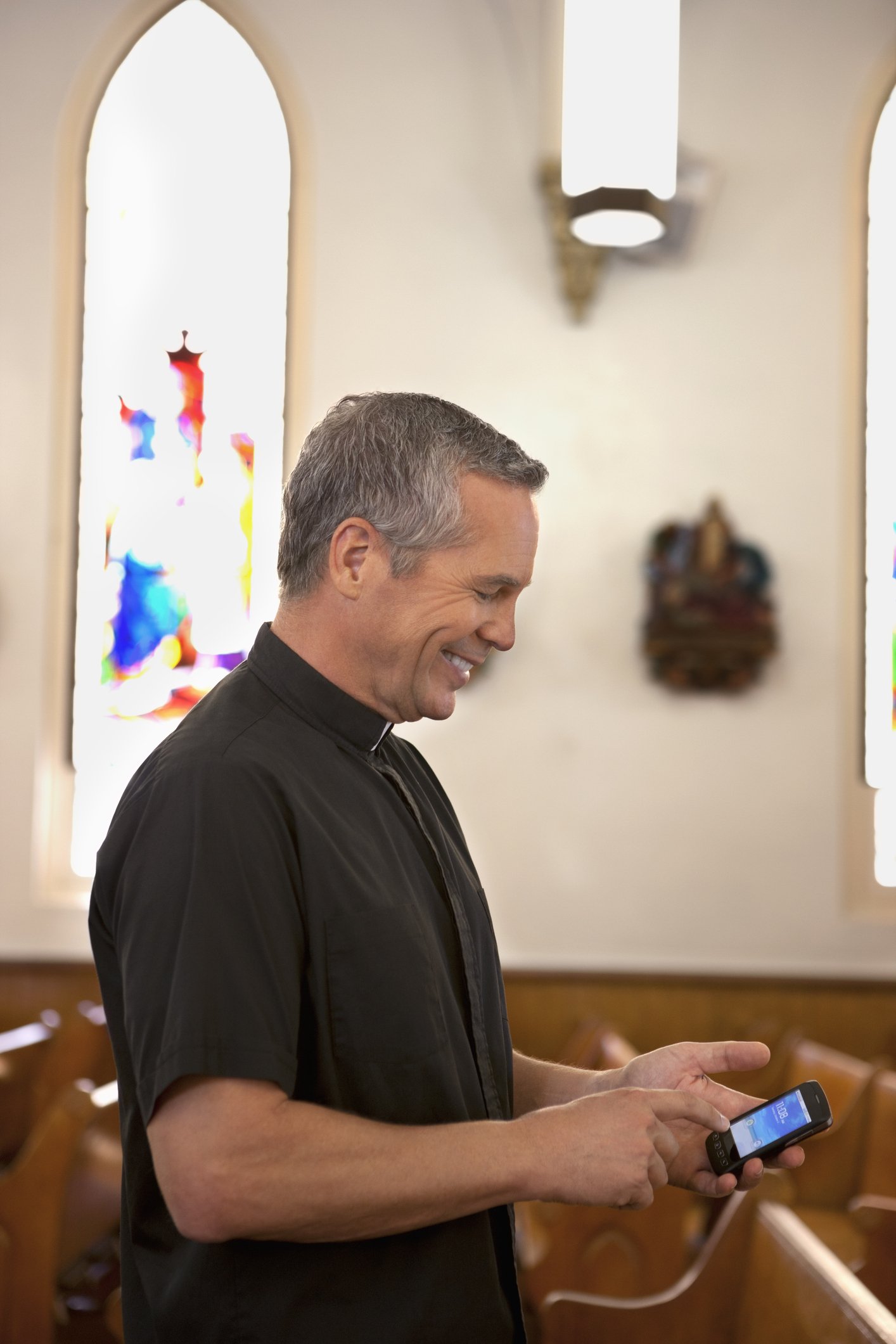 Foto eines Priesters bei der Benutzung eines Handys in der Kirche | Quelle: Getty Images