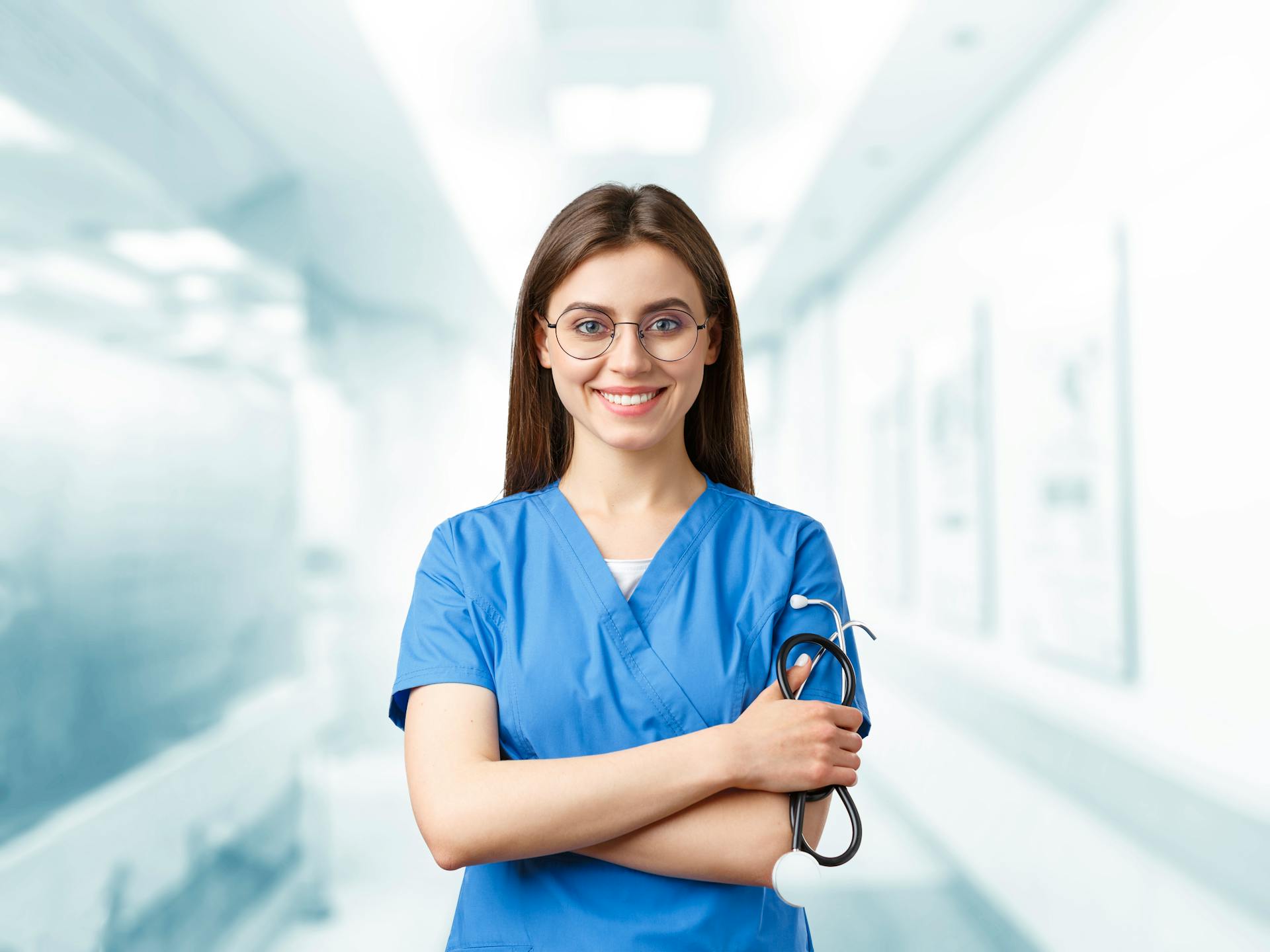 A young woman in blue scrubs smiles while holding a stethoscope | Source: Pexels