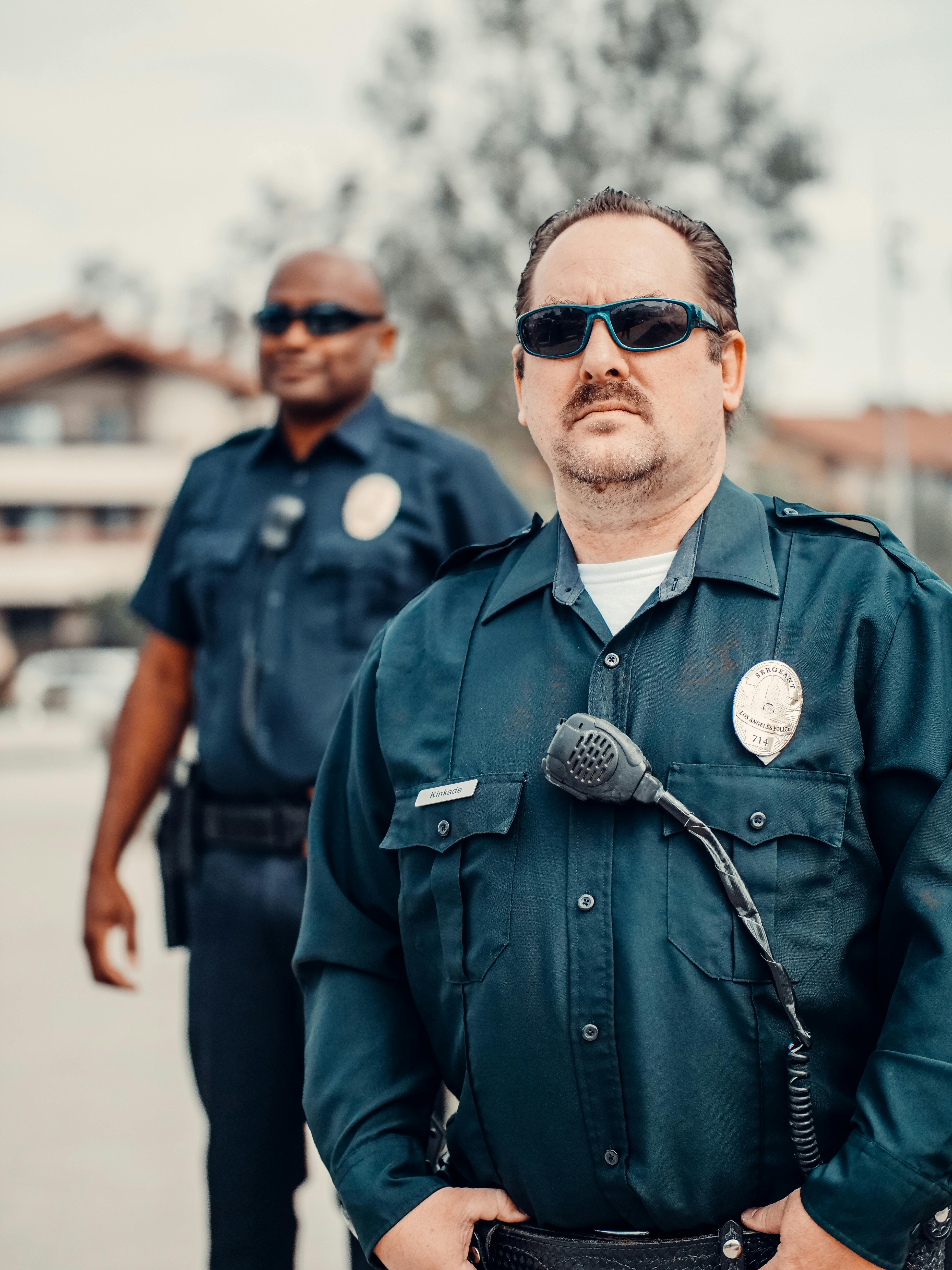 A somber-looking policeman standing behind a colleague | Source: Pexels